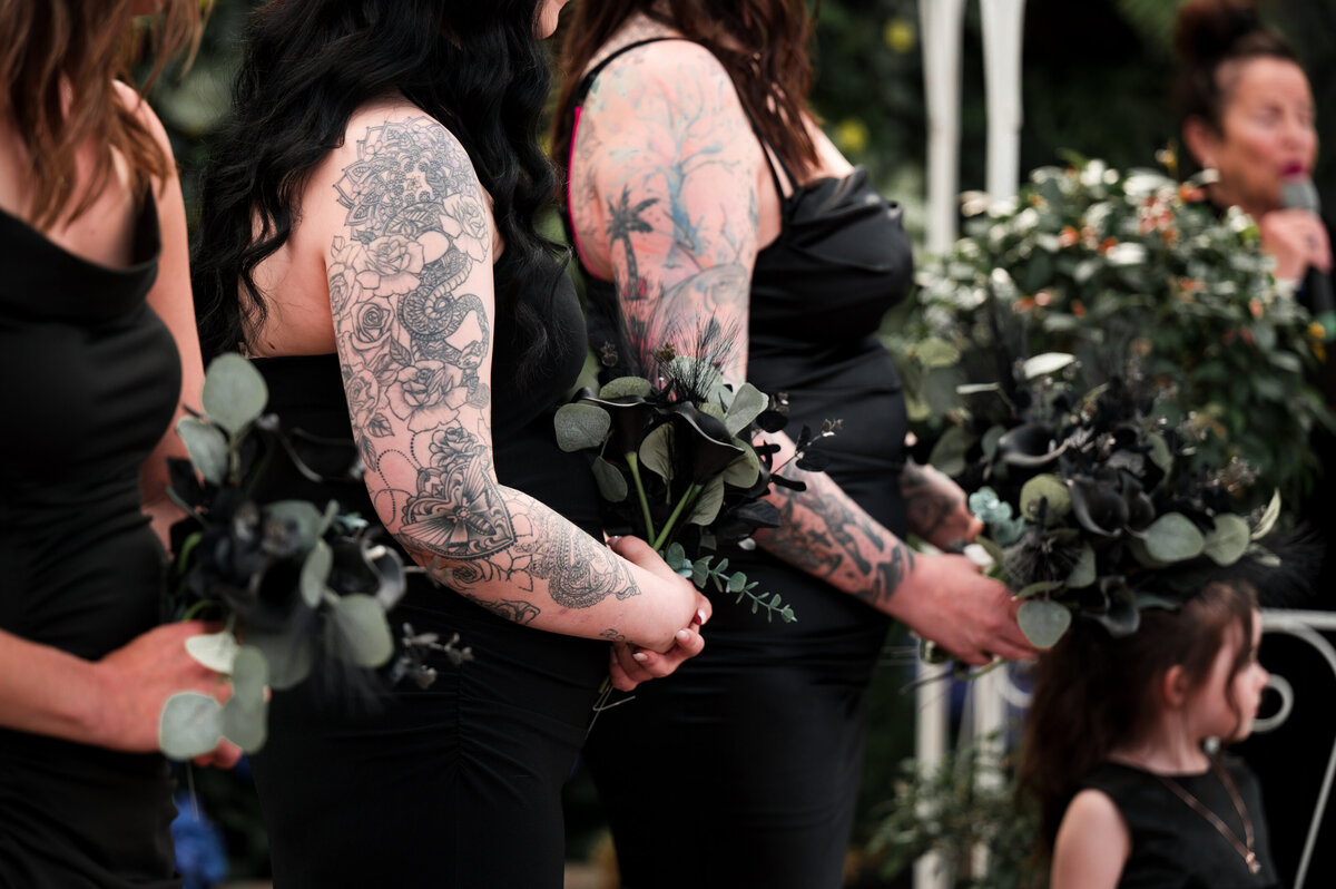 bridesmaids standing in a line during the wedding ceremony looking at the couple with pride
