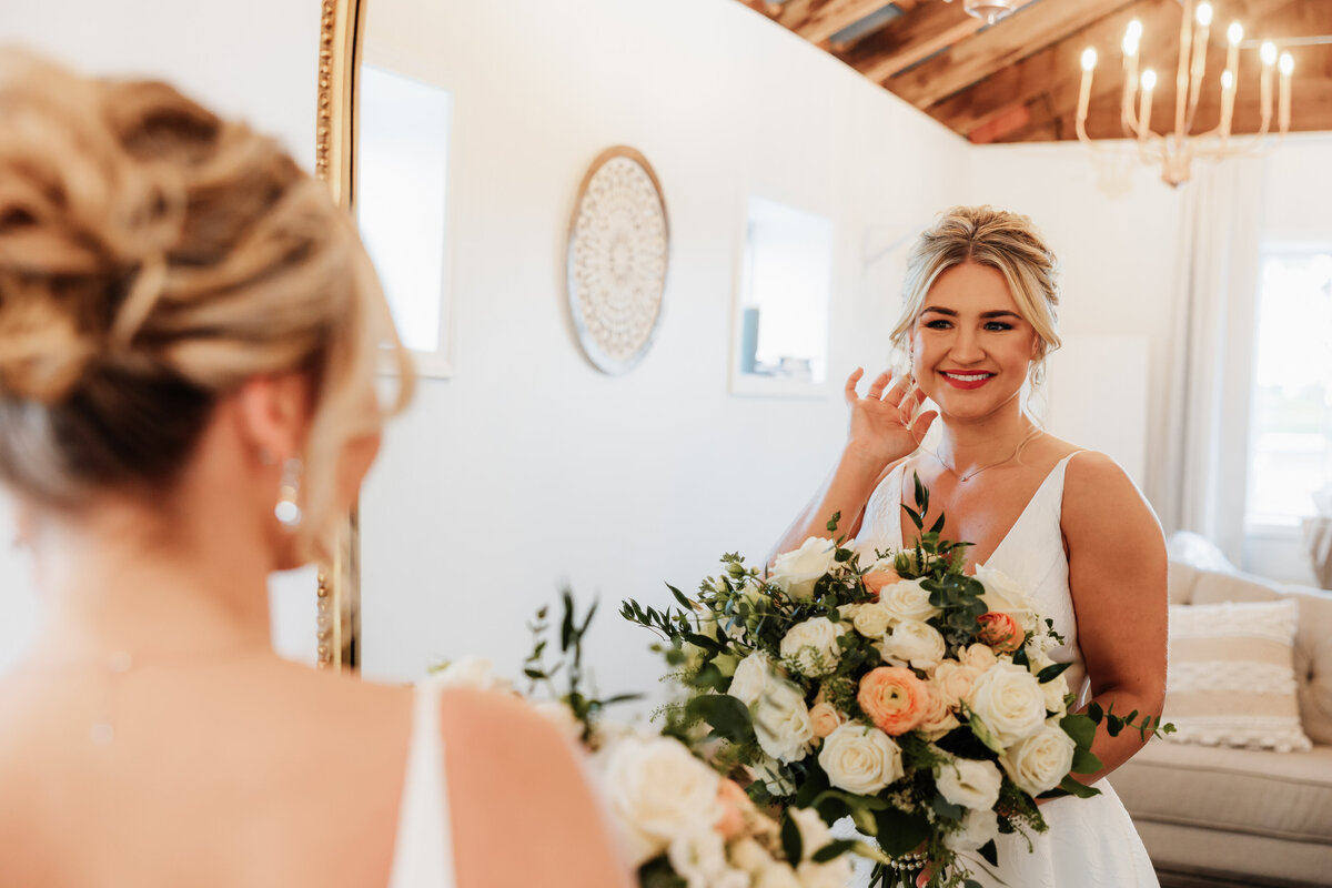 A bride admires herself in the mirror of her bridal suite.