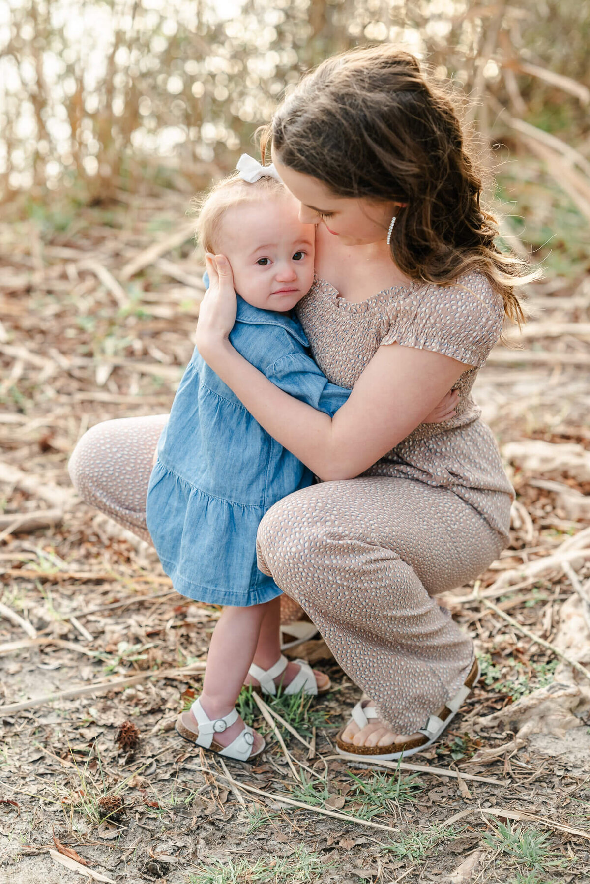 A toddler wearing blue hugs her mom close during a family photoshoot near Moyock, NC.