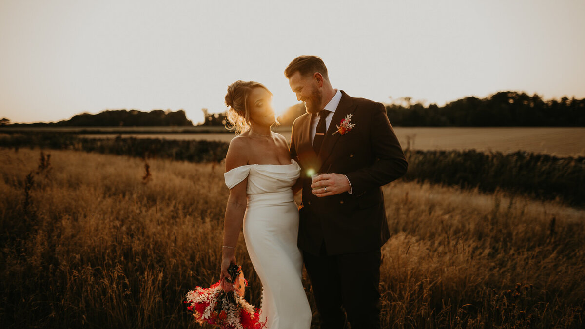 Bride and groom in the fields at Lapstone Barn during golden hour. 
