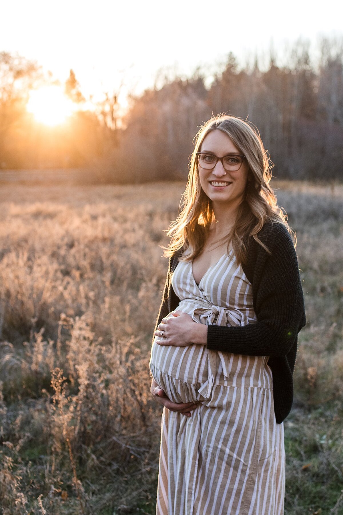 image of pregnant woman at sunrise holding belly