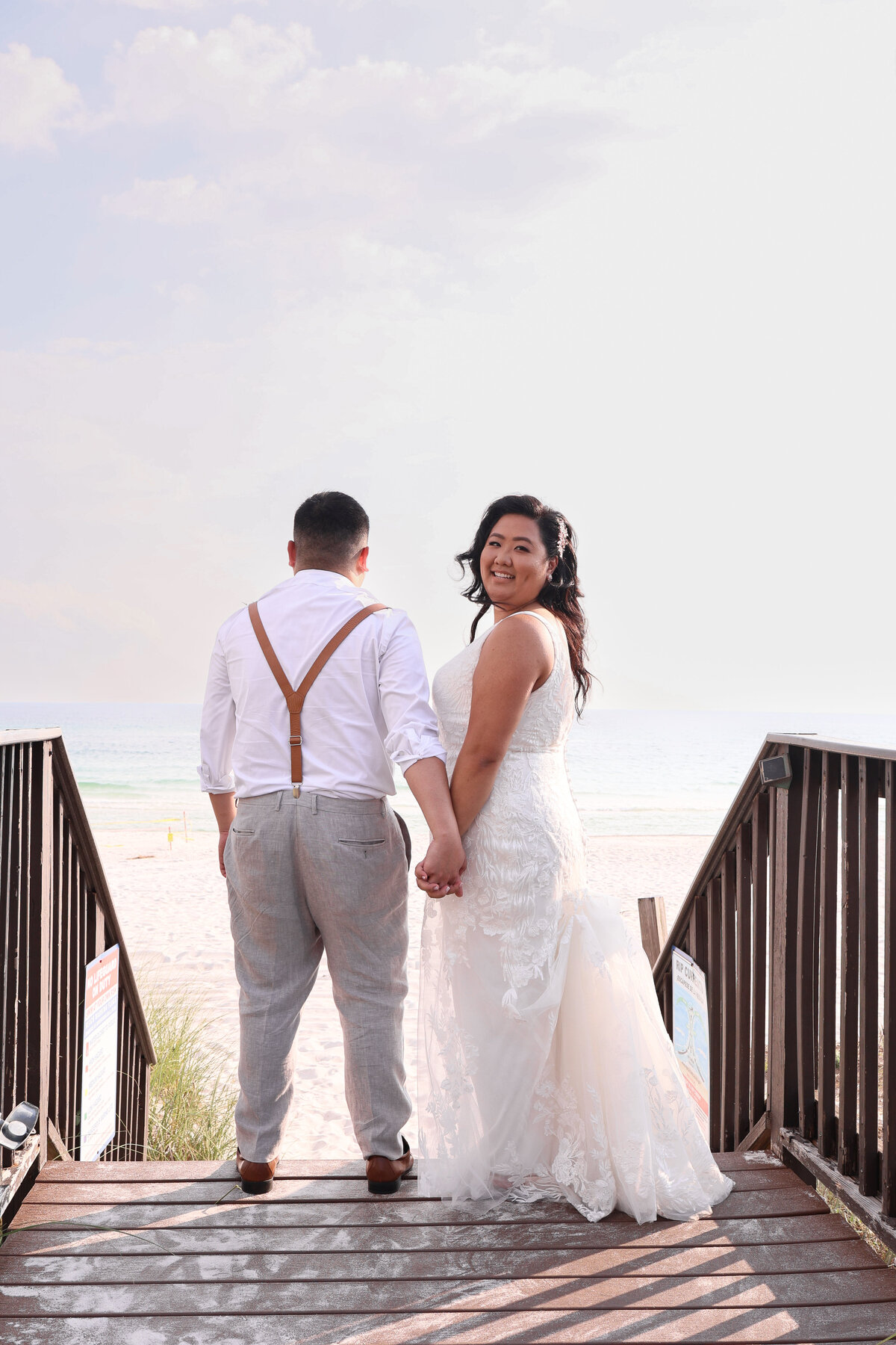 bride and groom holding hands while bride looks over her shoulder on boardwalk at runaway island restaurant  florida