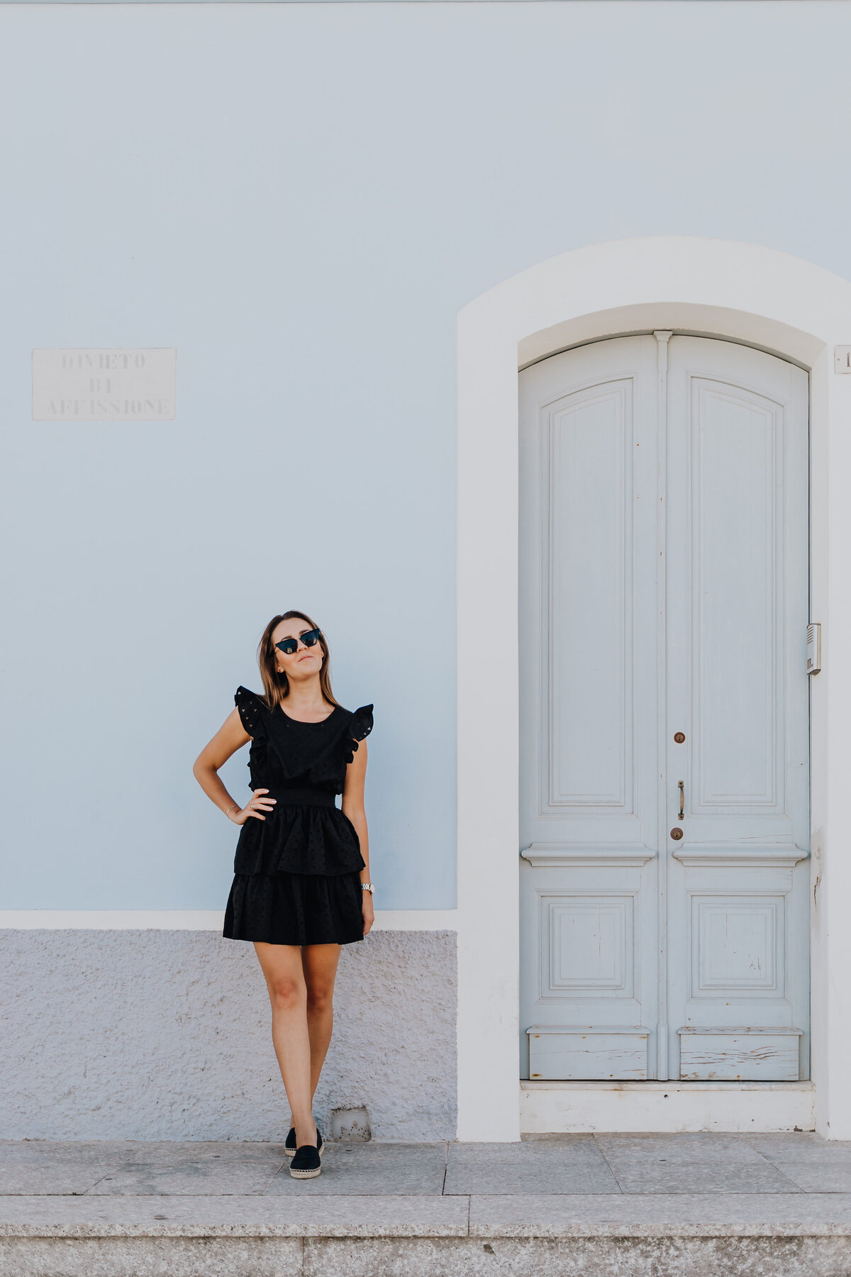 kaboompics_a-young-woman-with-dark-hair-wearing-a-black-dress-poses-by-the-blue-building-18700