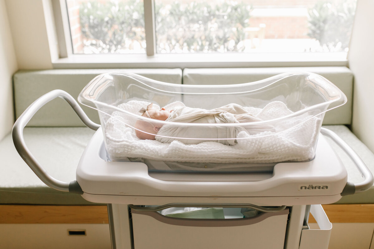 newborn baby in hospital bassinet by window