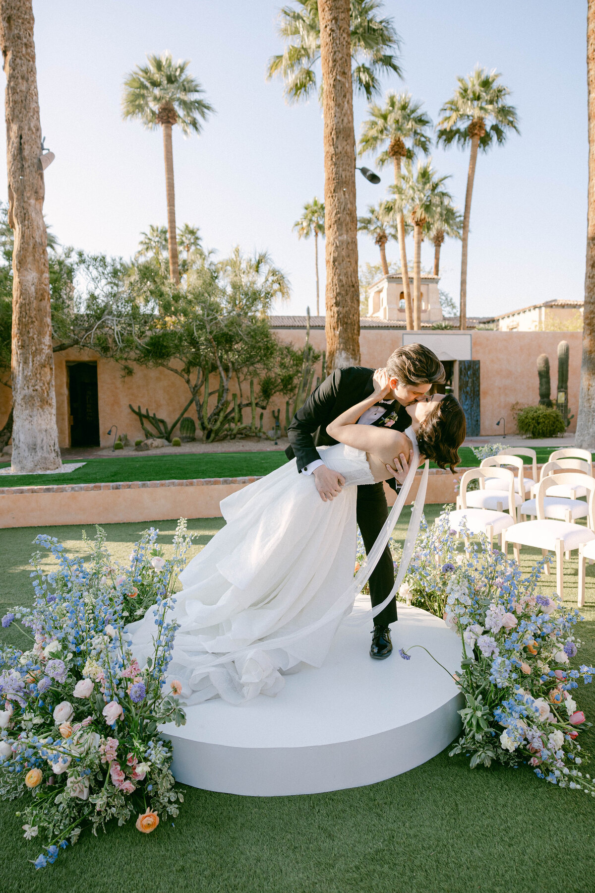 Bride and groom share first kiss during wedding ceremony on Vernadero Lawn at Royal Palms.