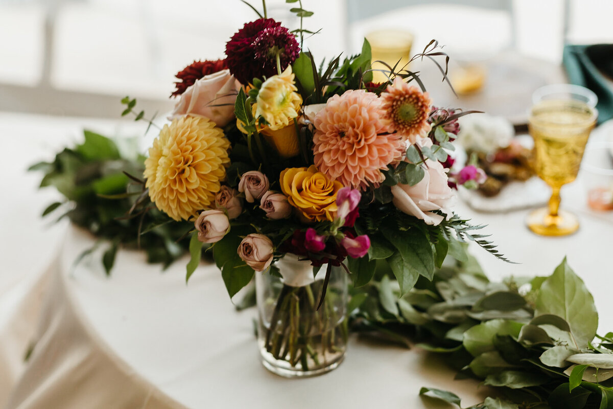 Fall colored bridal bouquet with peach, blush, yellow, and burgundy flowers.