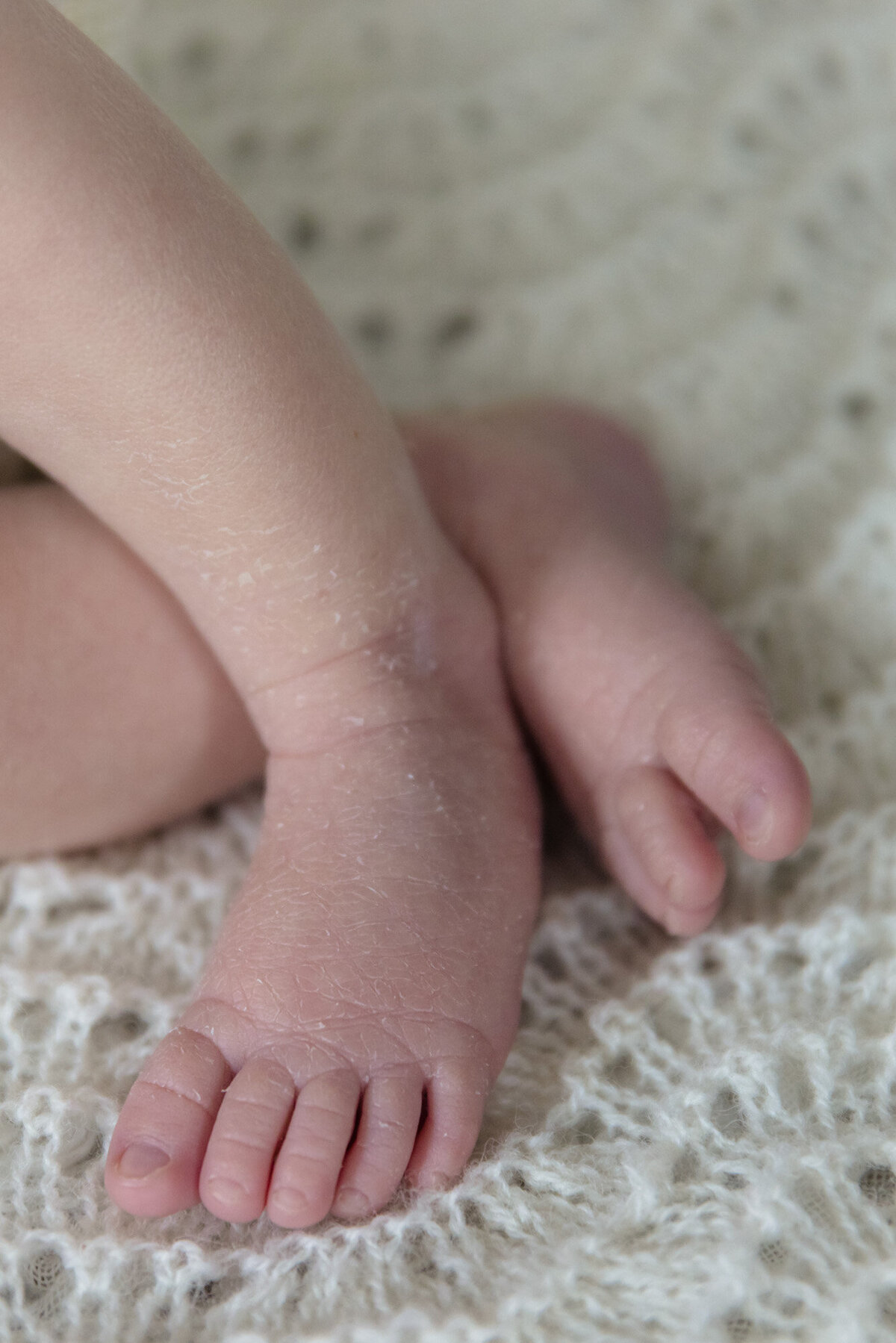 Detajlbilde av en babys fot, på et strikket hvitt pledd. Fotografert i Studio Landmark, Fyllingsdalen.