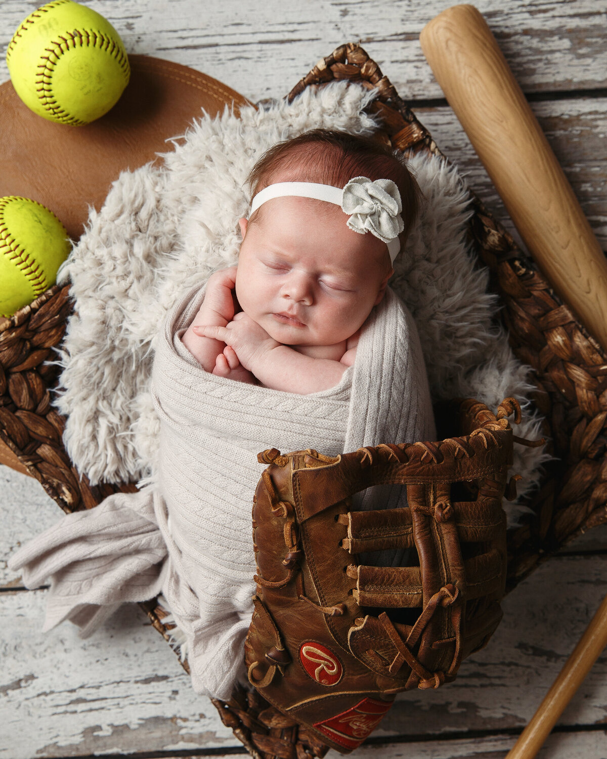 Newborn baby girl sitting inside a catchers mitt