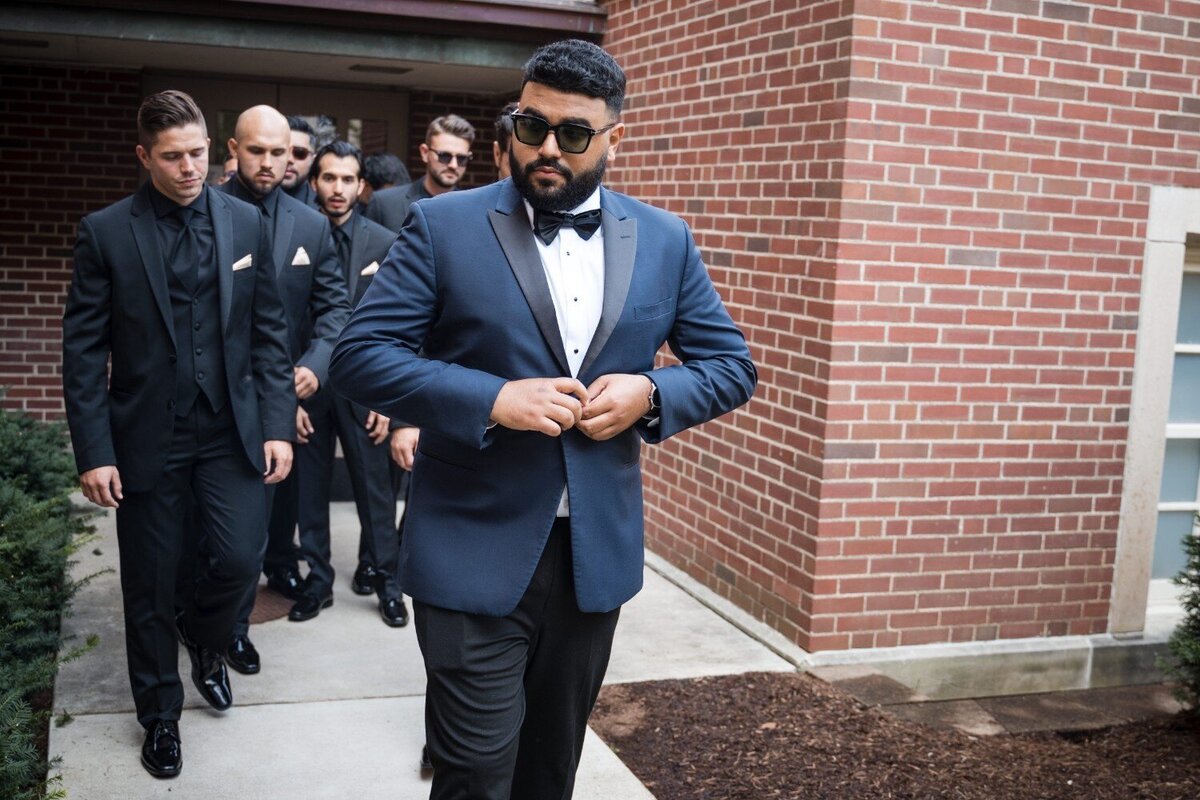 Groom leads groomsmen in tuxedos outside Union Club Hotel before ceremony.