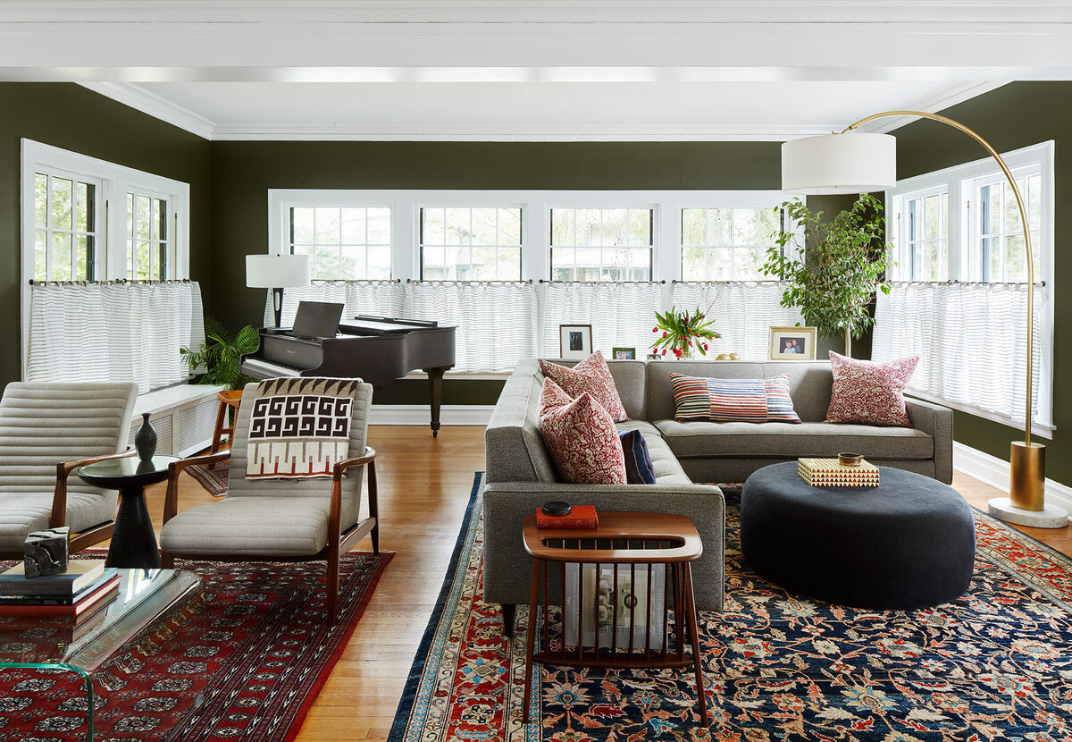 Living room with olive green walls and neutral furniture with patterned rugs