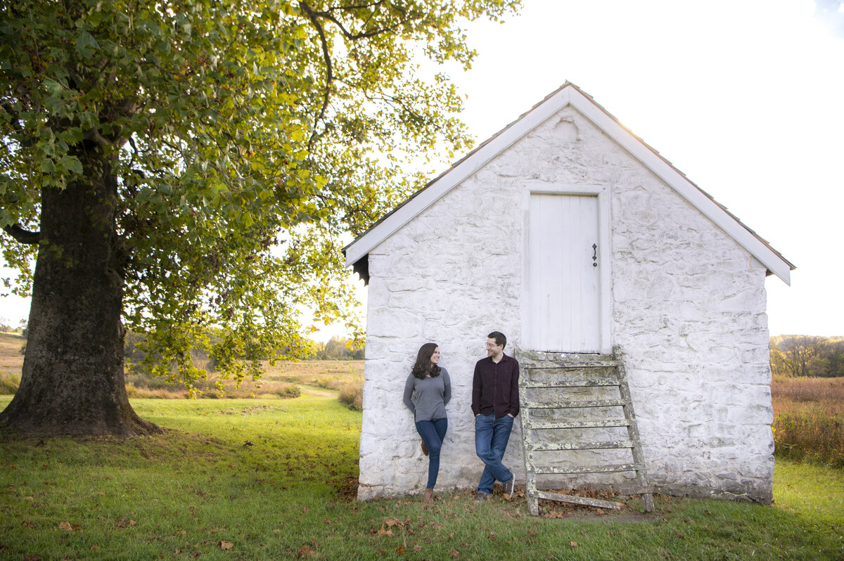 A couple standing together against the wall of a small building 