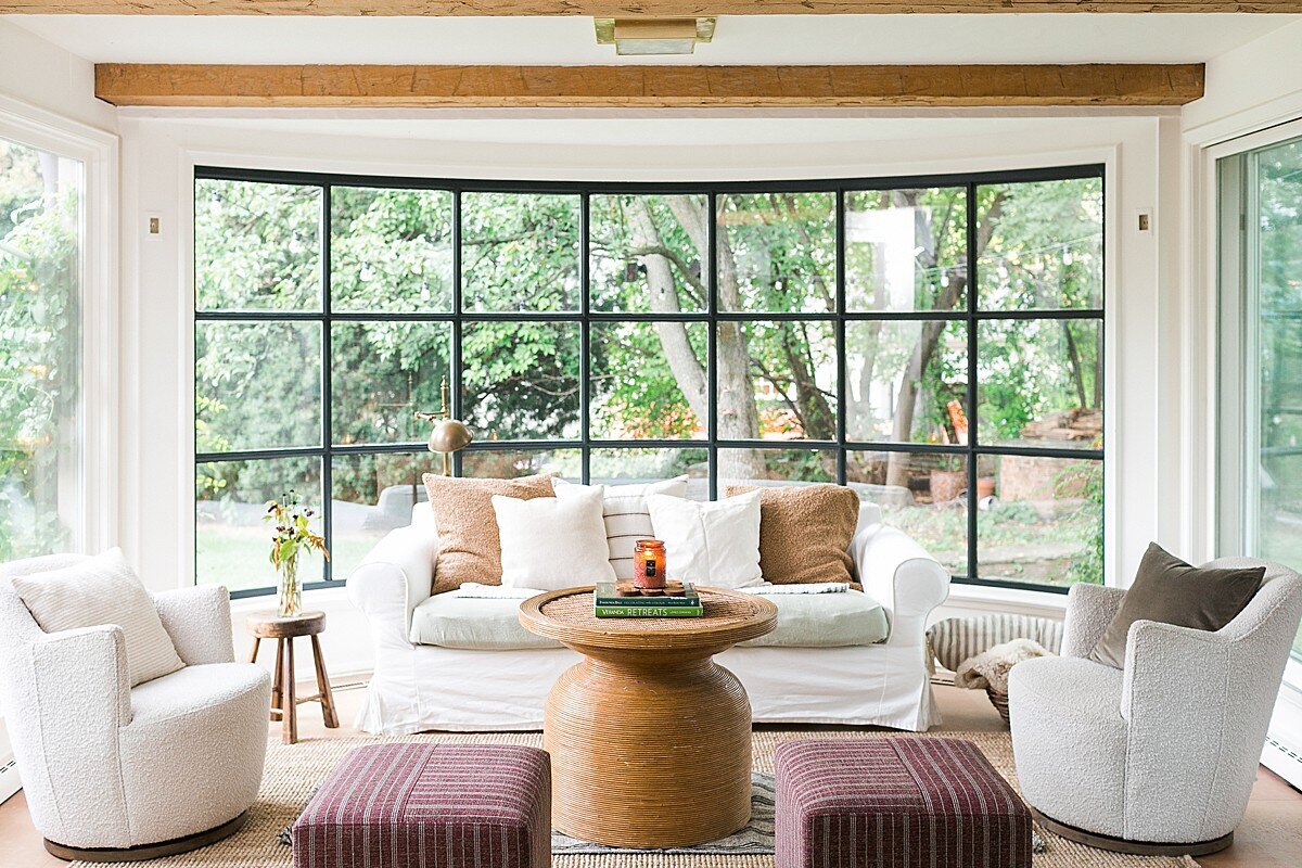interior living room with white couches and a large window with a coffee table in the middle and a candle burning lit in the middle