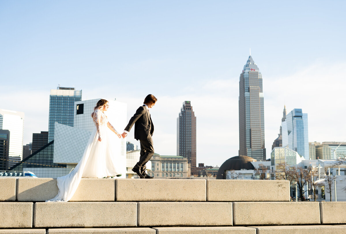 candid photo of wedding couple walking in front of the Cleveland skyline