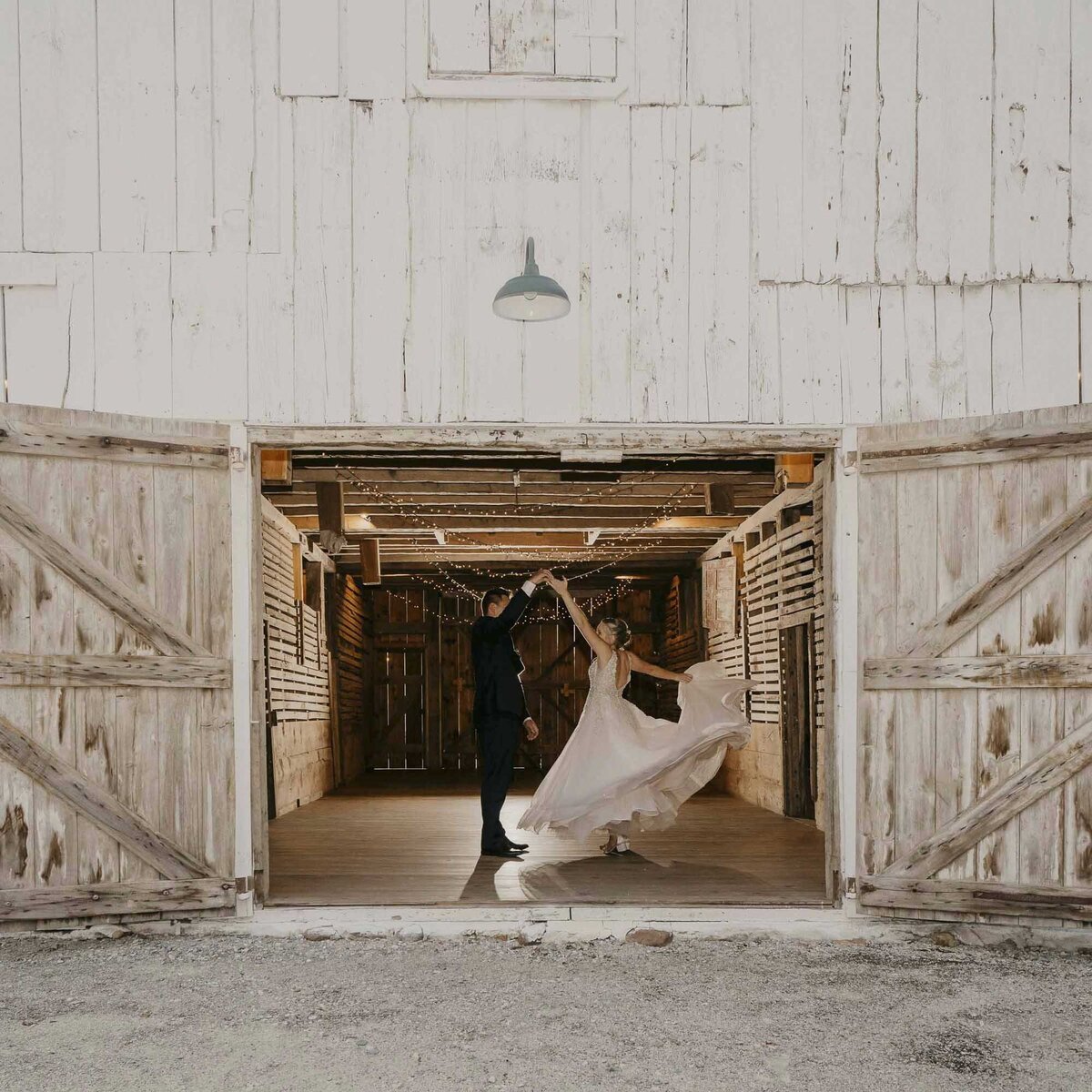 bride and groom twirling in a barn
