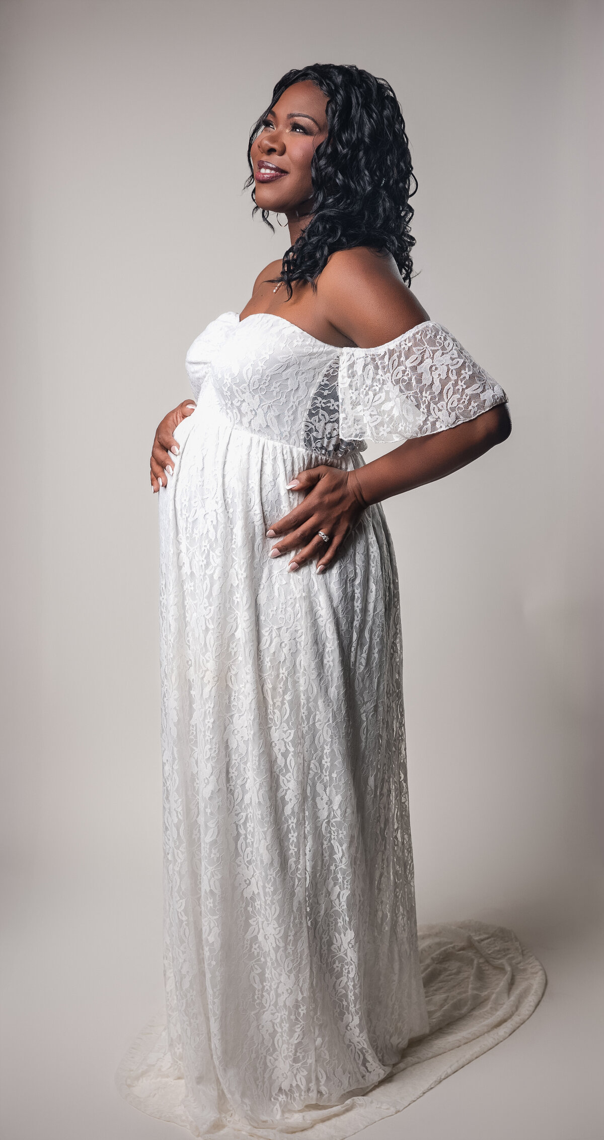 Mom to be posing for maternity session in a cream dress