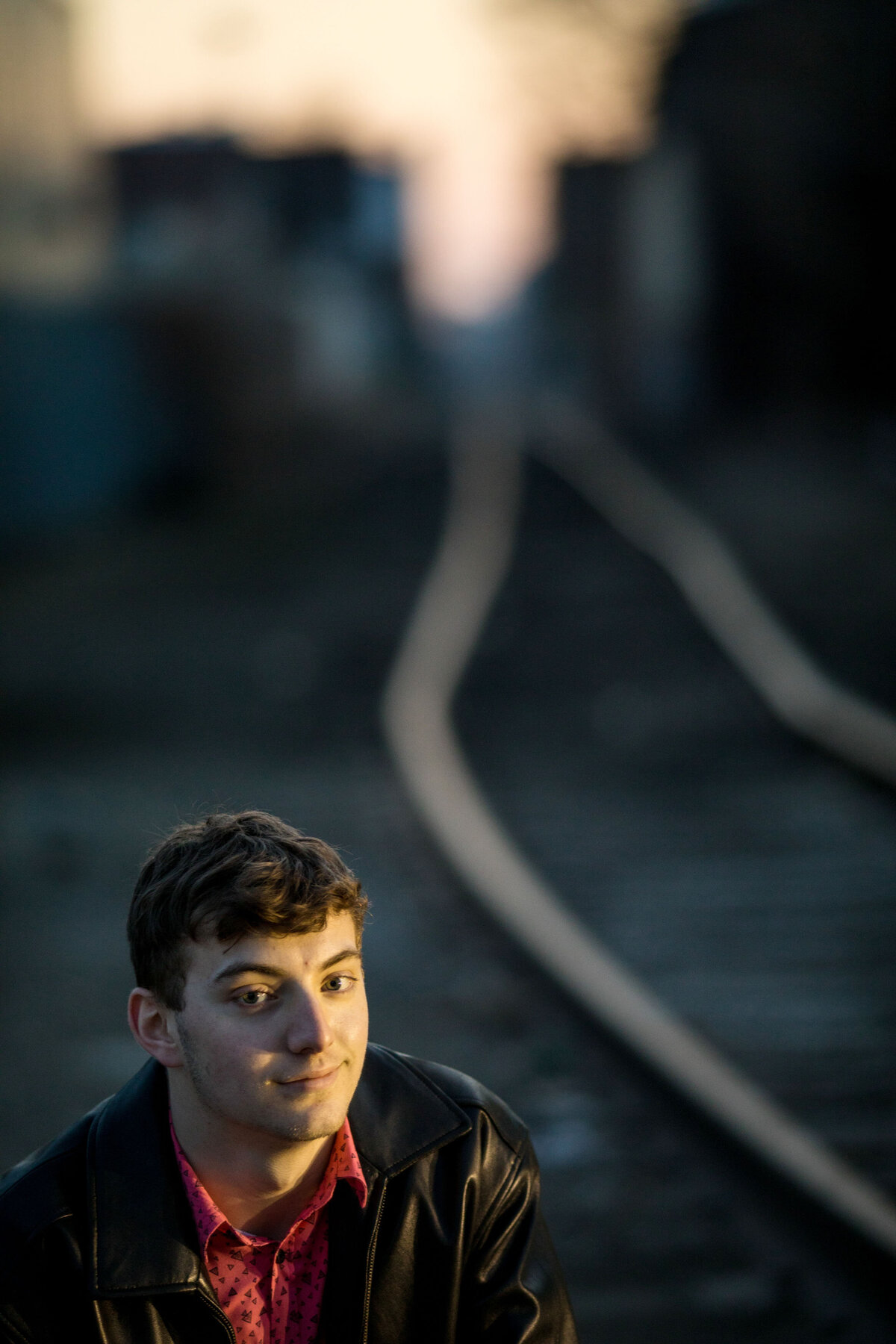 Off the railroad tracks the senior is lit by the sun.