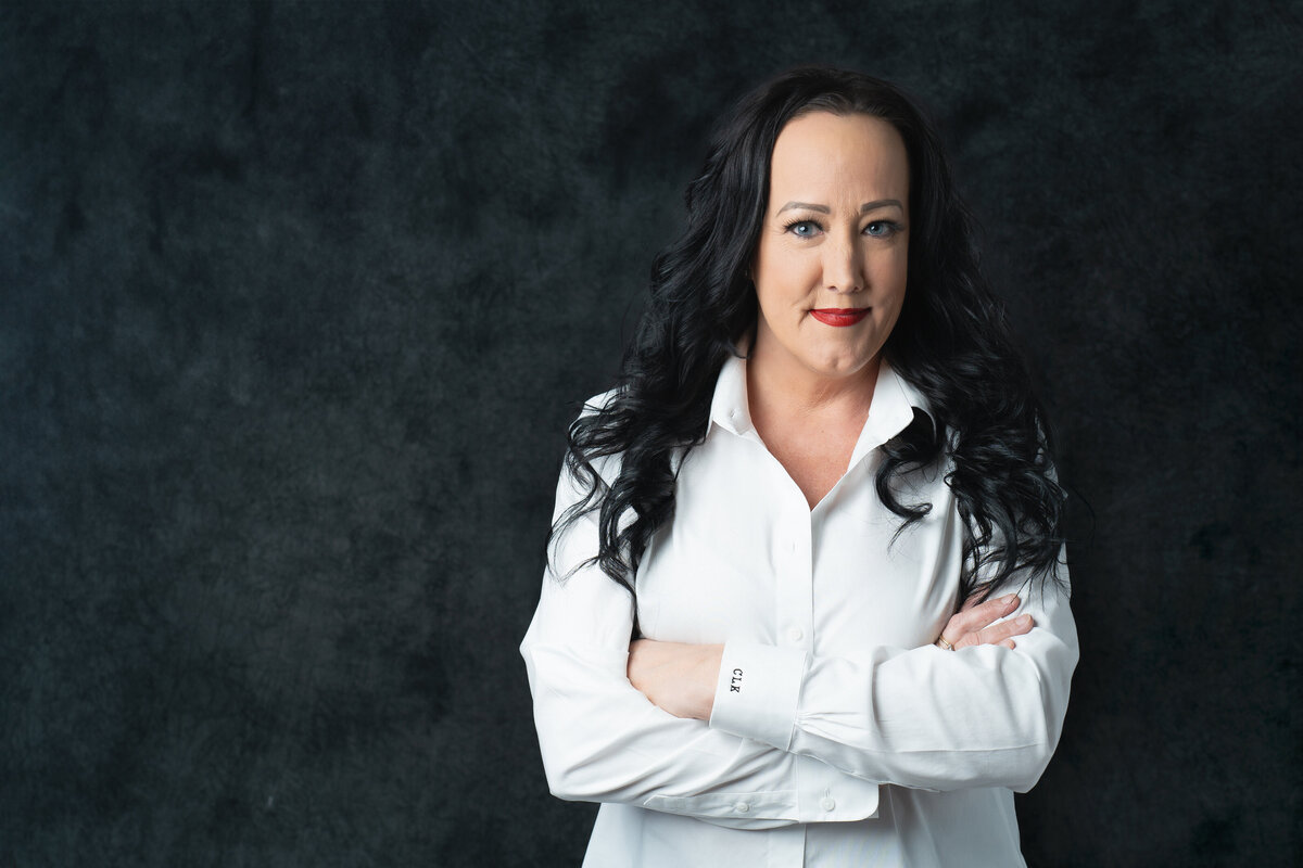 headshot of a woman wearing white blouse,, arms crossed in a boss pose