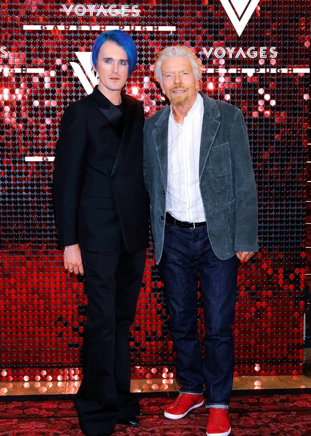Gareth Pugh and Richard Branson at a Virgin Voyages Photoshoot with a red sequin backdrop at a luxury party