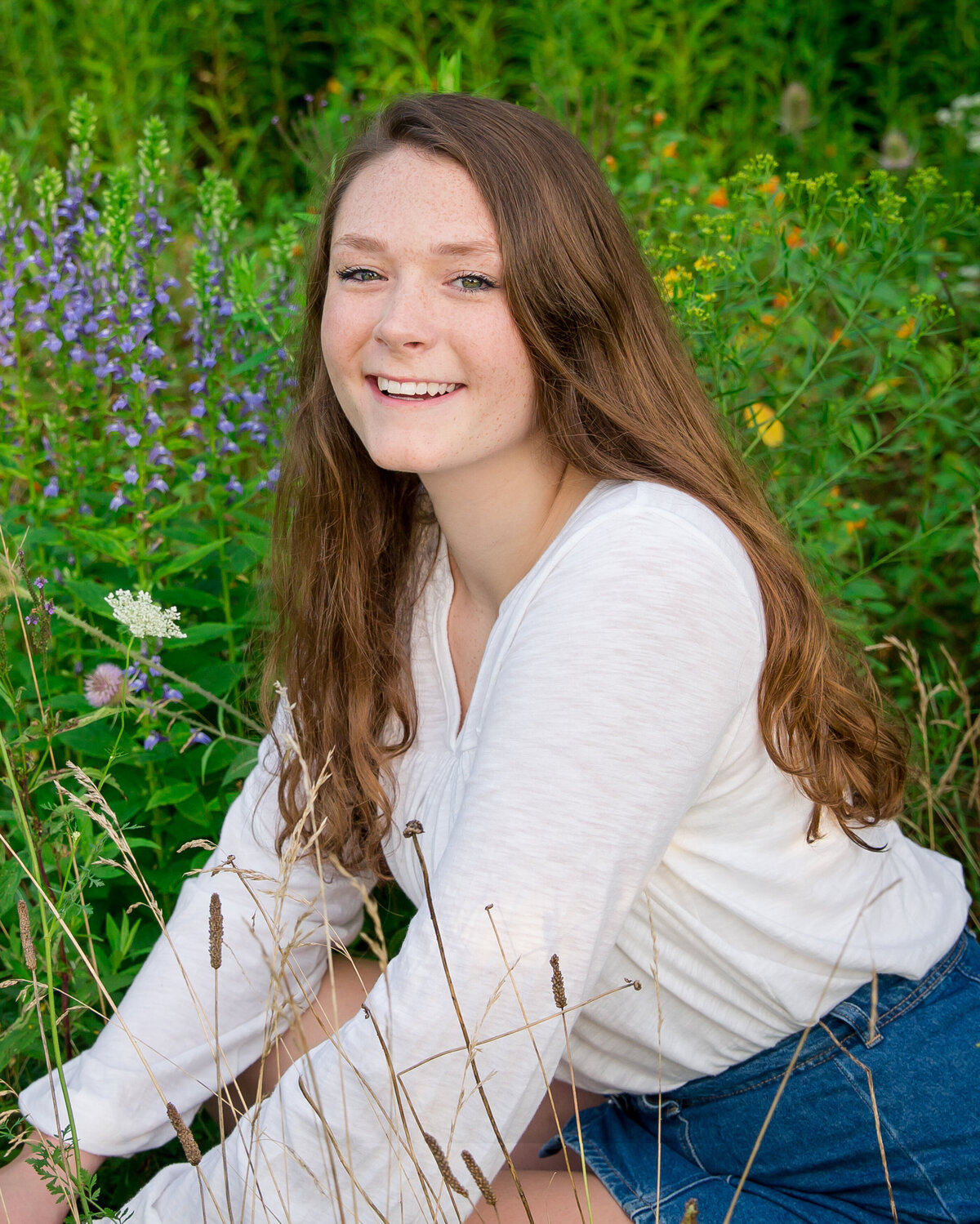 Senior picture near Keuka Lake with small purple flowers in the background