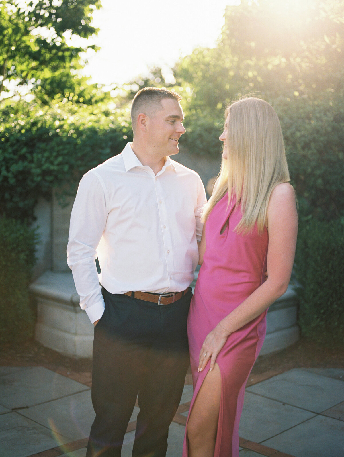 Engaged couple smiling at each other in front of Columbus park fountain shot by Philadelphia photographer.