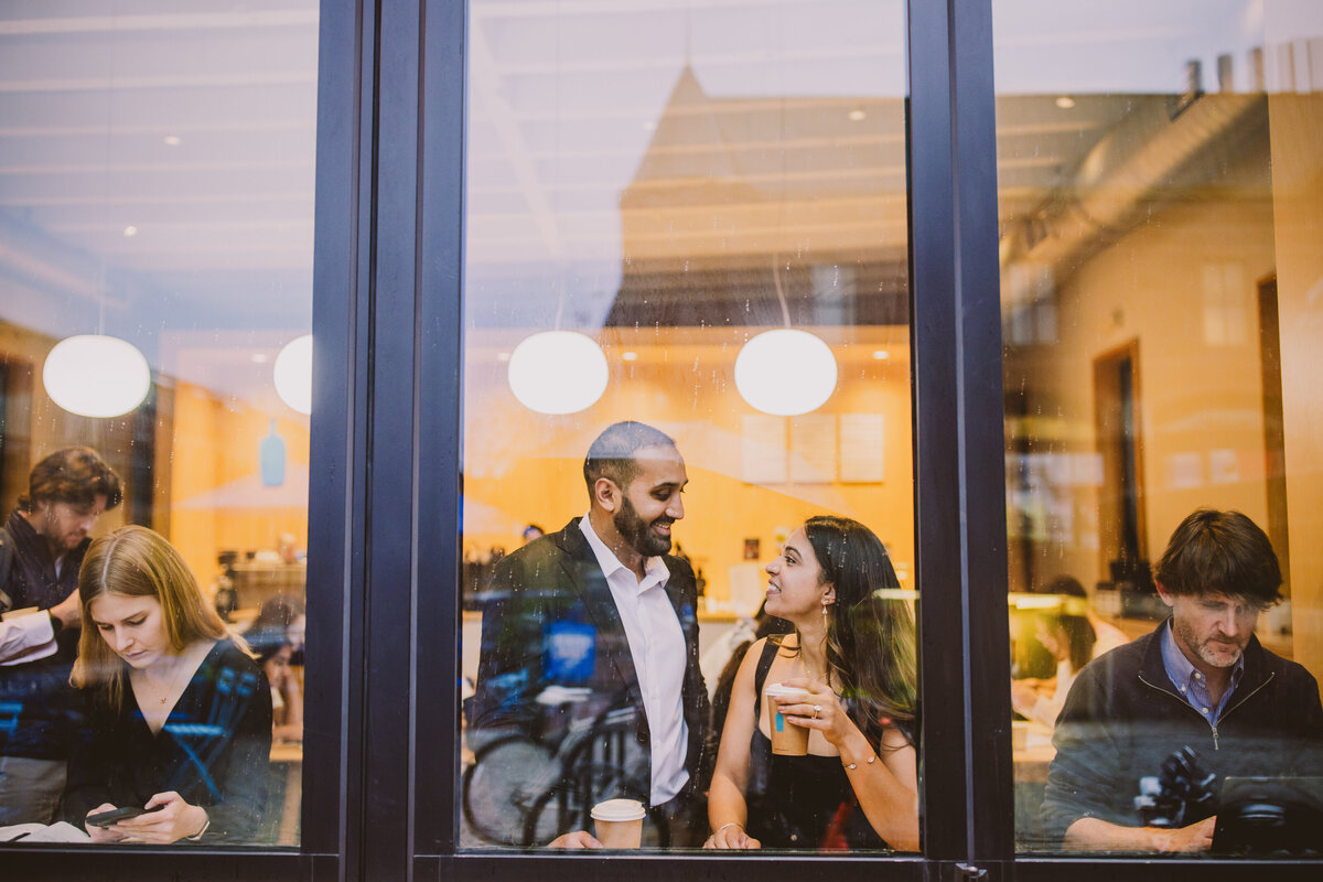 an engaged couple having coffee together in front of a window at blue bottle coffee in georgetown dc
