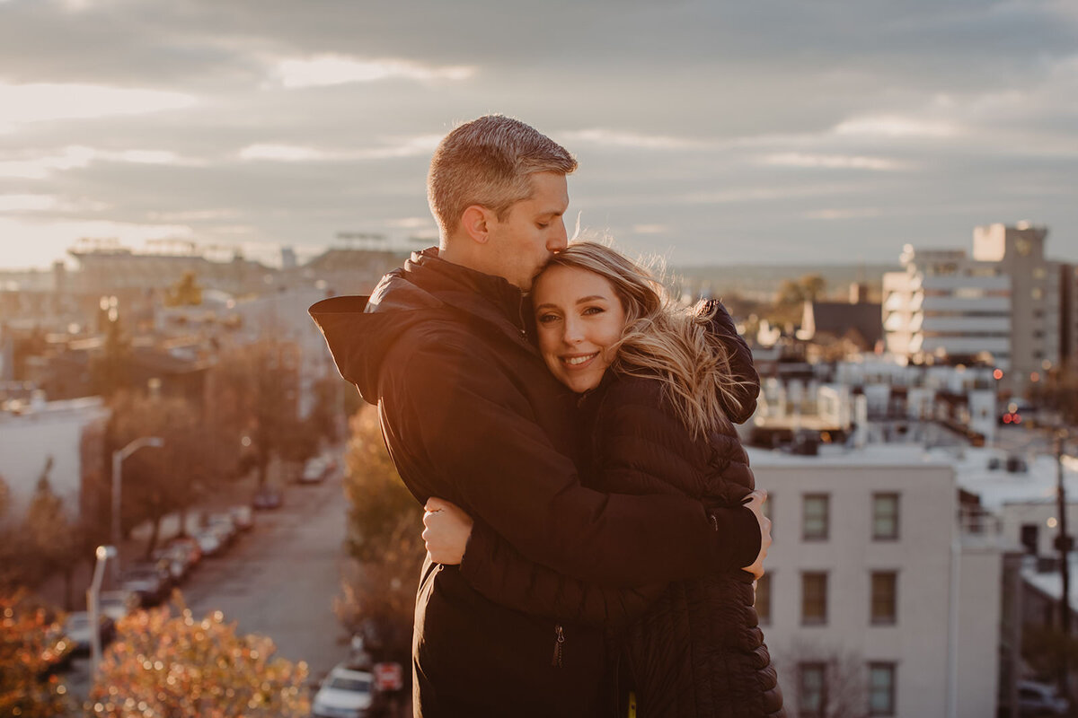 A person kissing their partner's head as they hug 