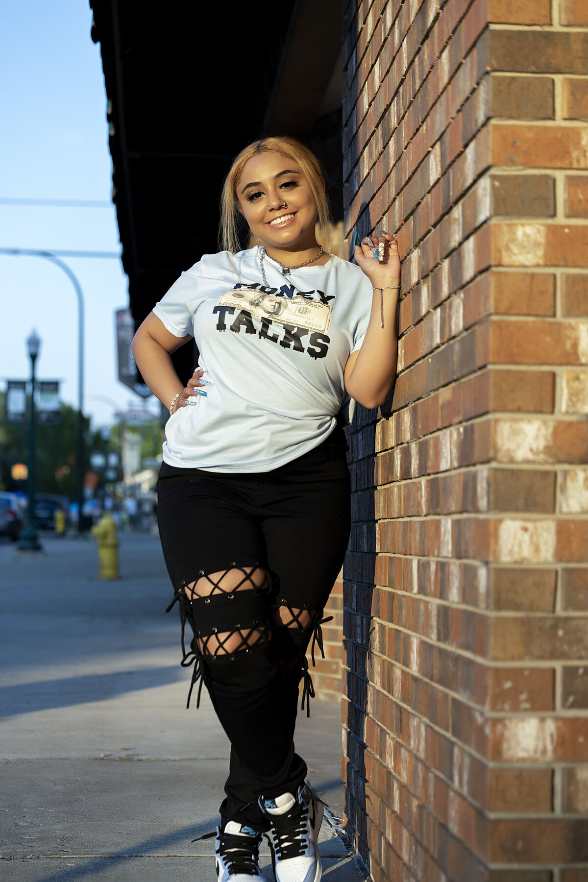 Downtown Ypsilanti Senior Photoshoot | Ypsilanti Michigan Senior Photographer, Senior girl with graphic light blue t-shirt and with black destructed jeans back posing causually against brick wall