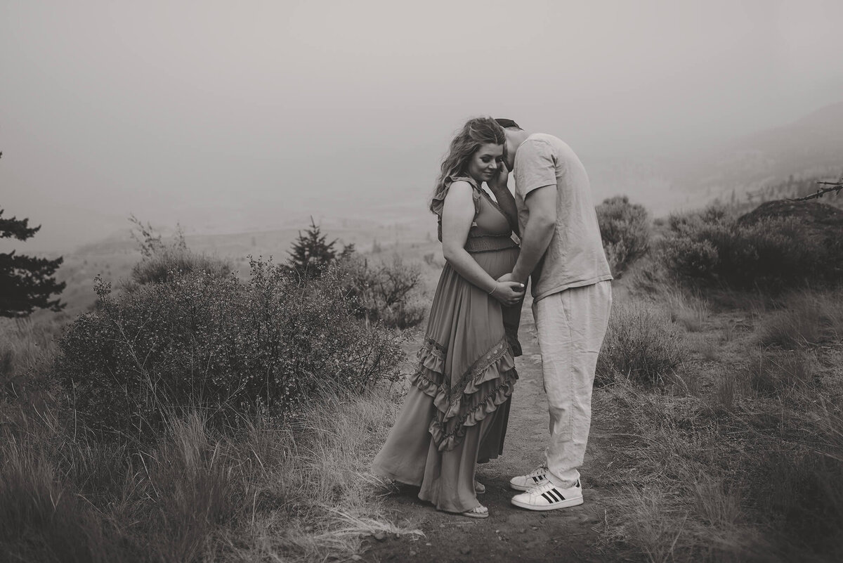 Brittany Danielle captures a black and white image of a couple embracing. The woman is pregnant wearing a beautiful dress.
