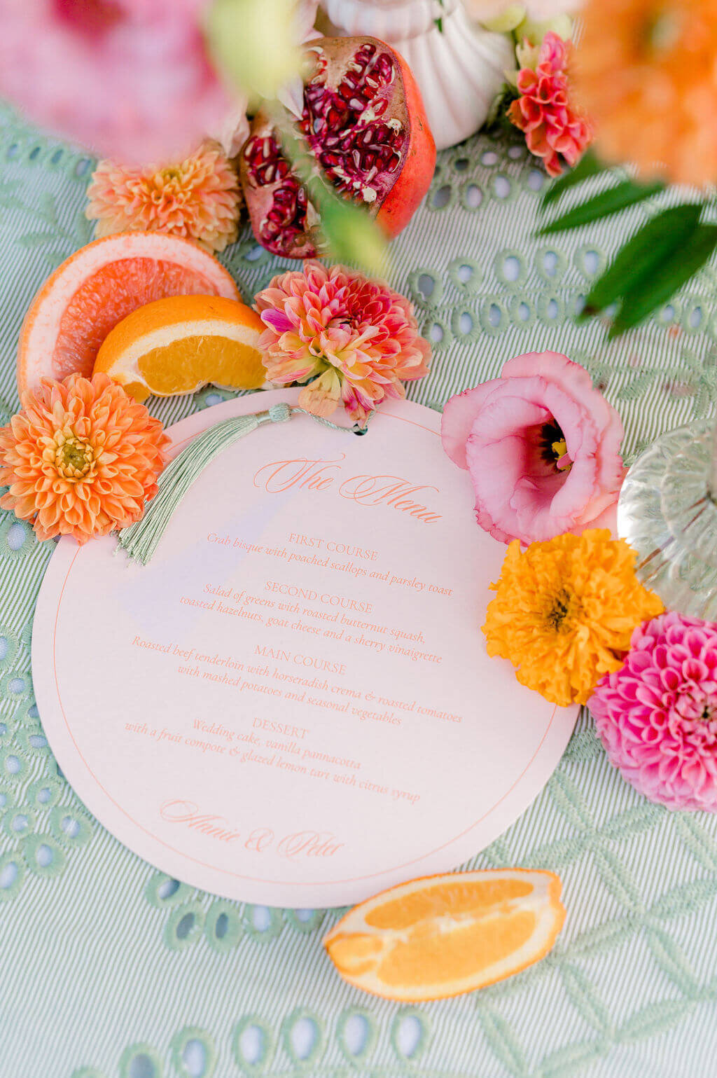 Round blush wedding menu with tassel, styled with citrus slices and florals. Keywords: wedding day stationery, wedding stationery, luxury wedding invitations, wedding invitation designer.