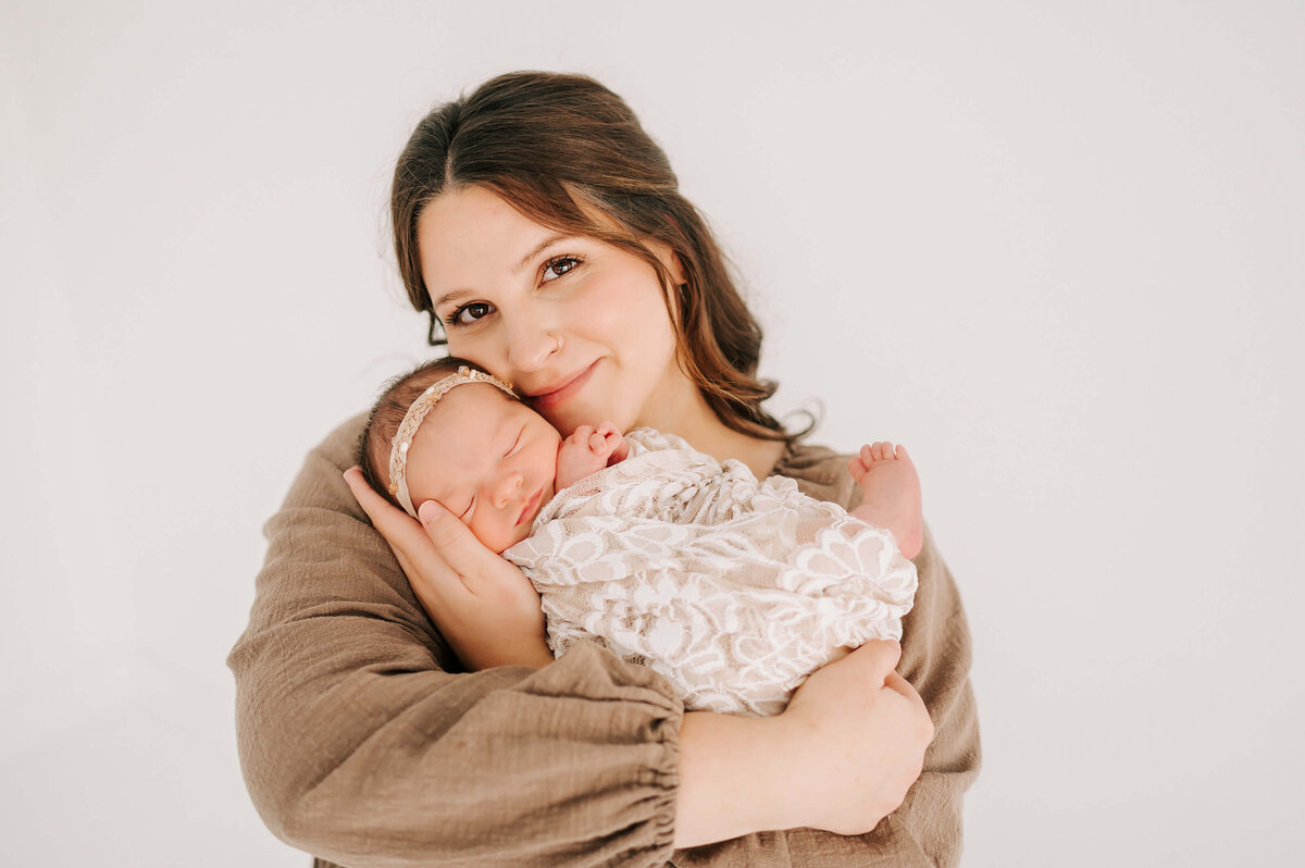 Branson MO newborn photographer Jessica Kennedy of The XO Photography captures mom holding newborn baby girl in swaddle