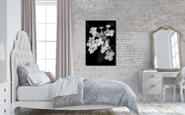 Fine Art Flower Photography Metal Print Black and White closeup of tine white flowers example display title Constellation handing on brick wall in bedroom next to vanity table and mirror behind bed facing to side