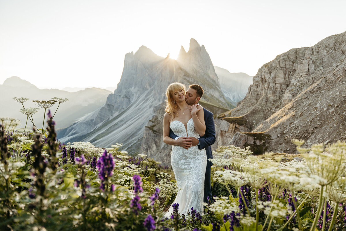 Bride and groom surrounded by purple wildflowers Dolomites