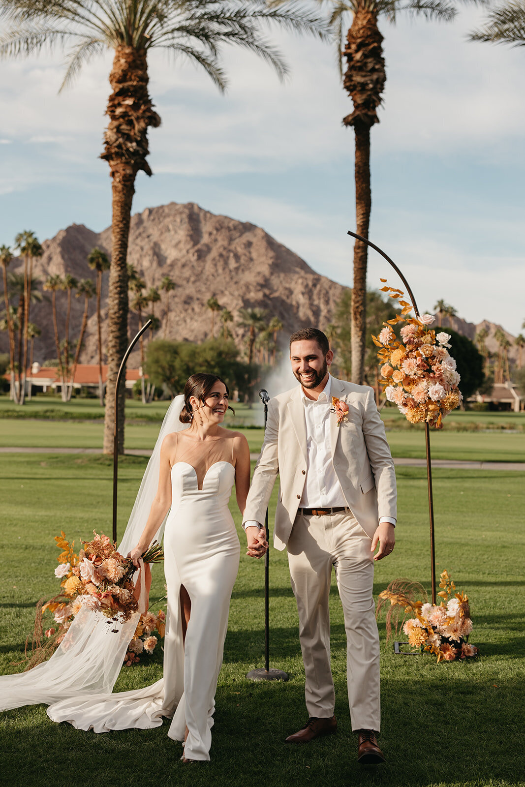 Bride and groom walking in front of their wedding ceremony arch at La Quinta Resort