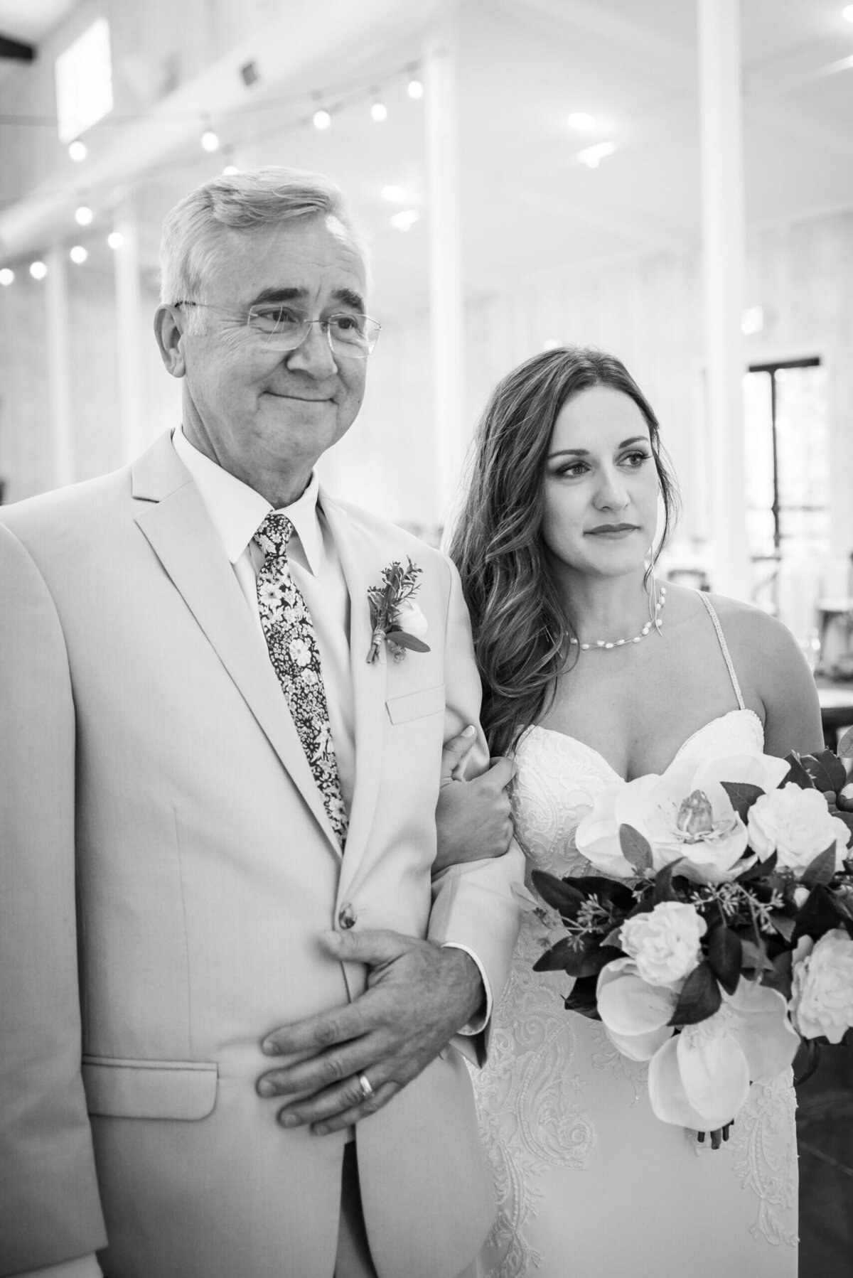 A sentimental candid moment of a bride arm-in-arm with her father as they get ready to walk up the aisle.