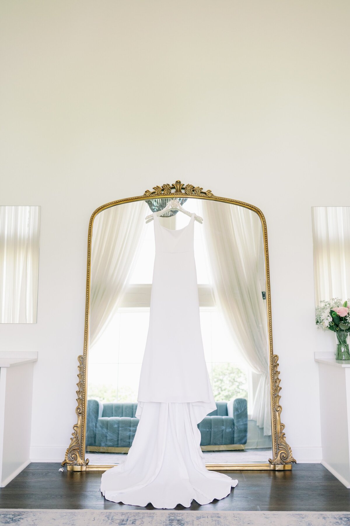a wedding dress hanging up in front of a mirror
