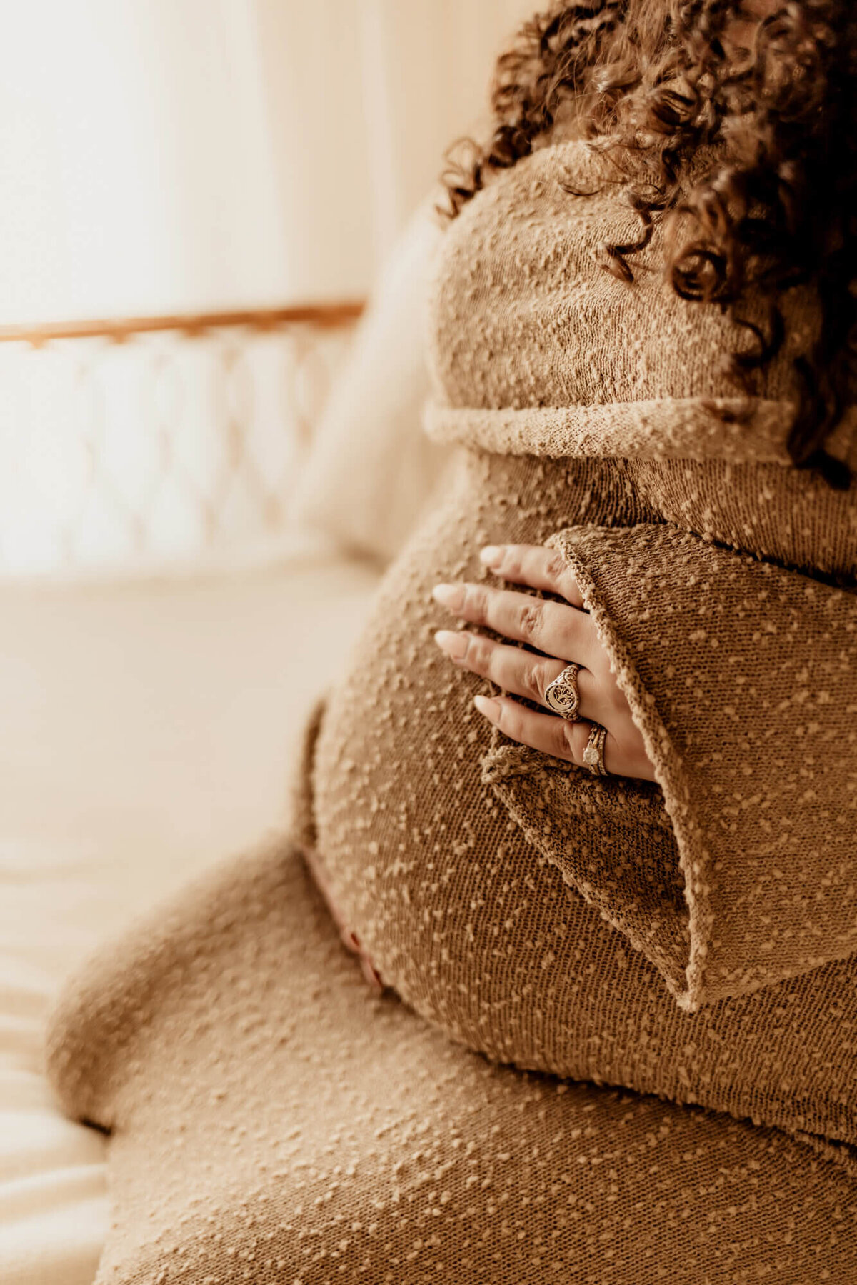 Woman with gold rings holds her pregnant belly, Mustang Oklahoma.