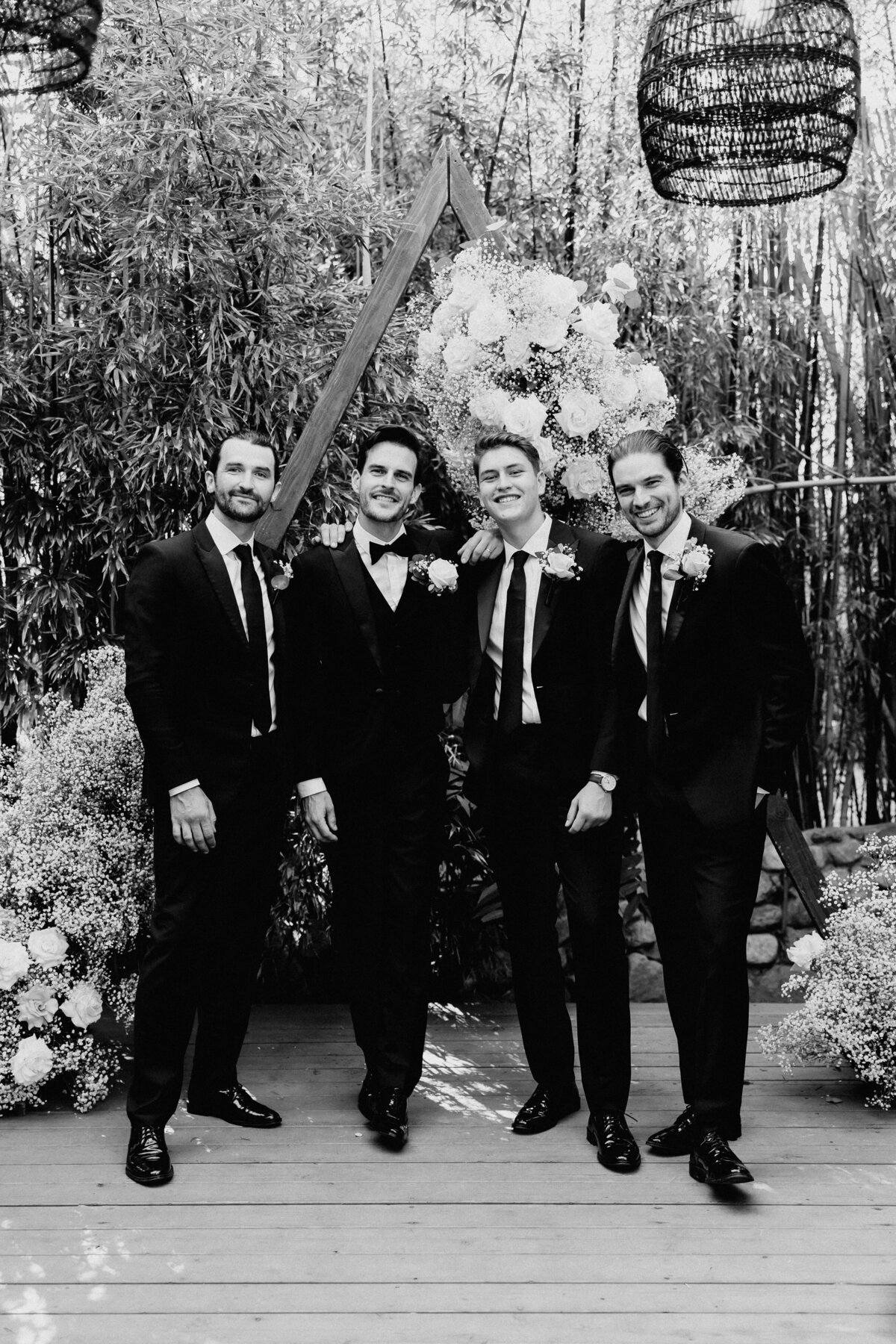 Elopement Photography, groom with groomsman pose for photo in black and white in front of ceremony arch
