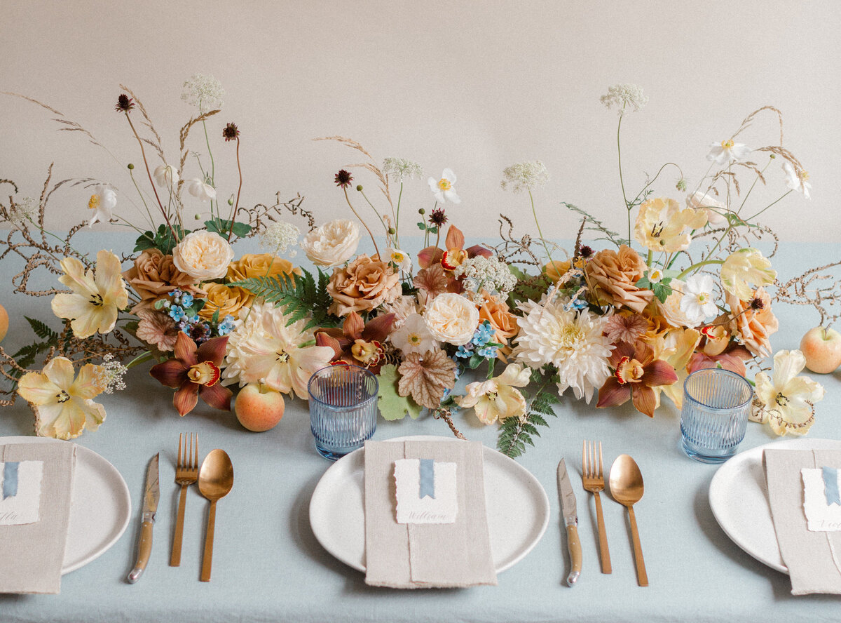 A lush, low centrepiece of orange and peach flowers at a Montreal wedding reception.