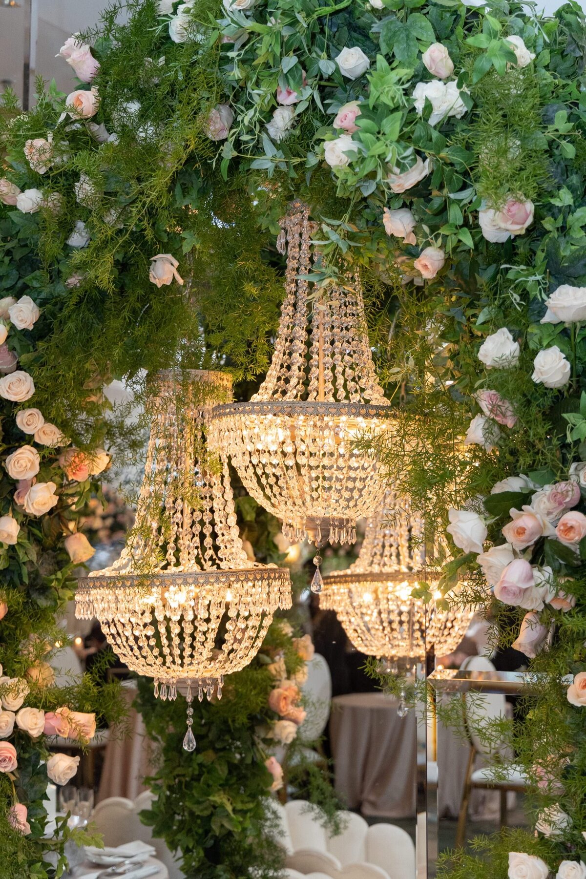 Chandeliers hanging from the ceiling surrounded by flowers