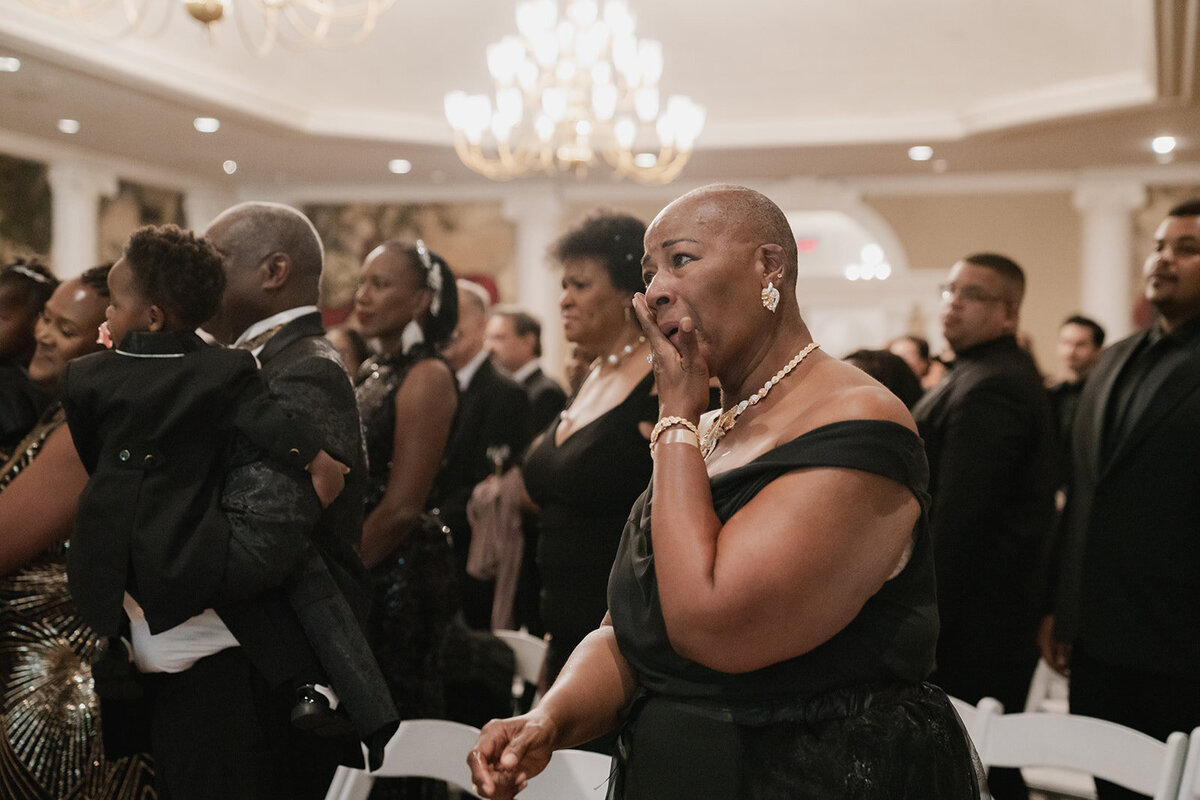 black wedding party guest wipes tears away