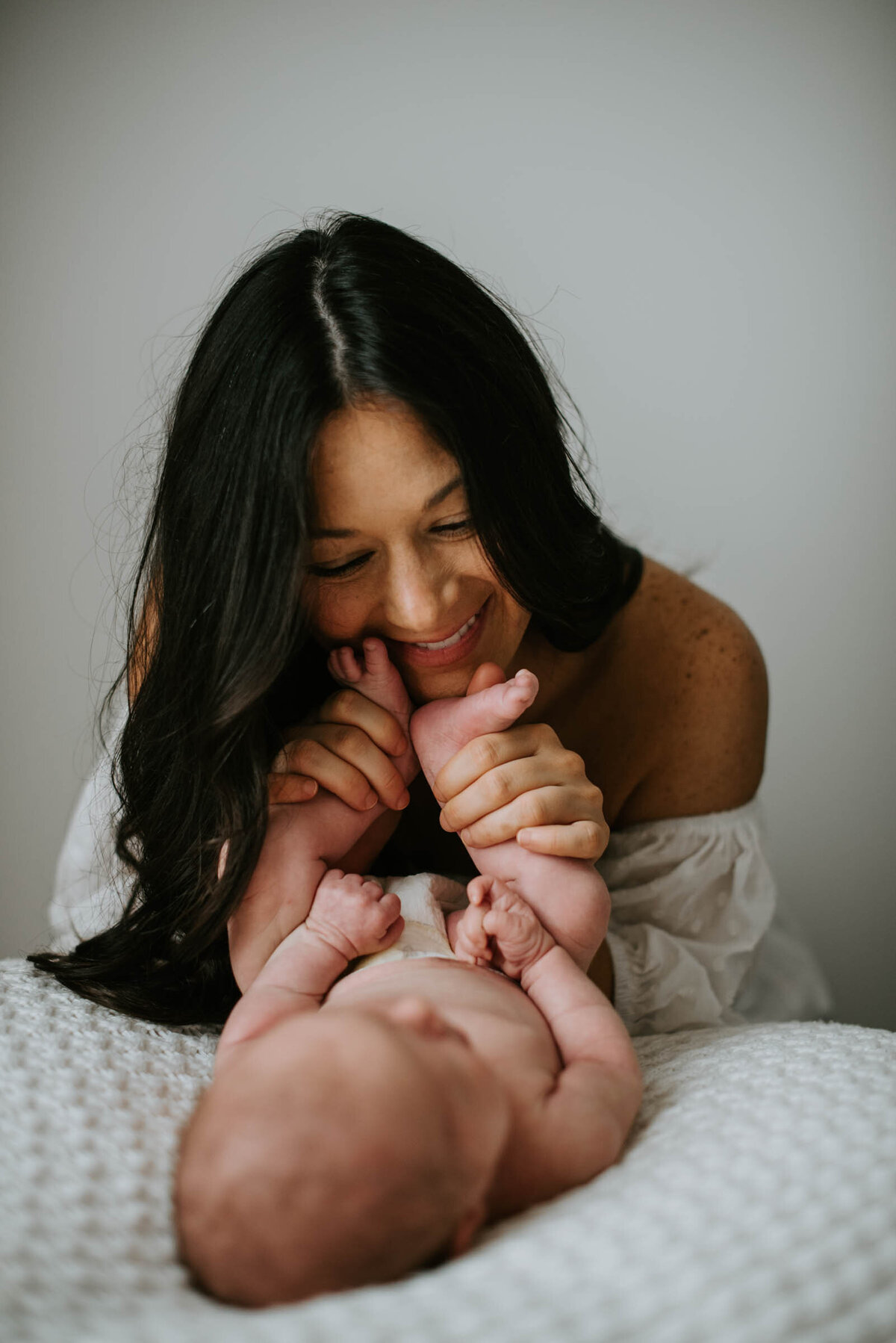 Mother kissing baby toes in the nursery Newborn Portrait Photography