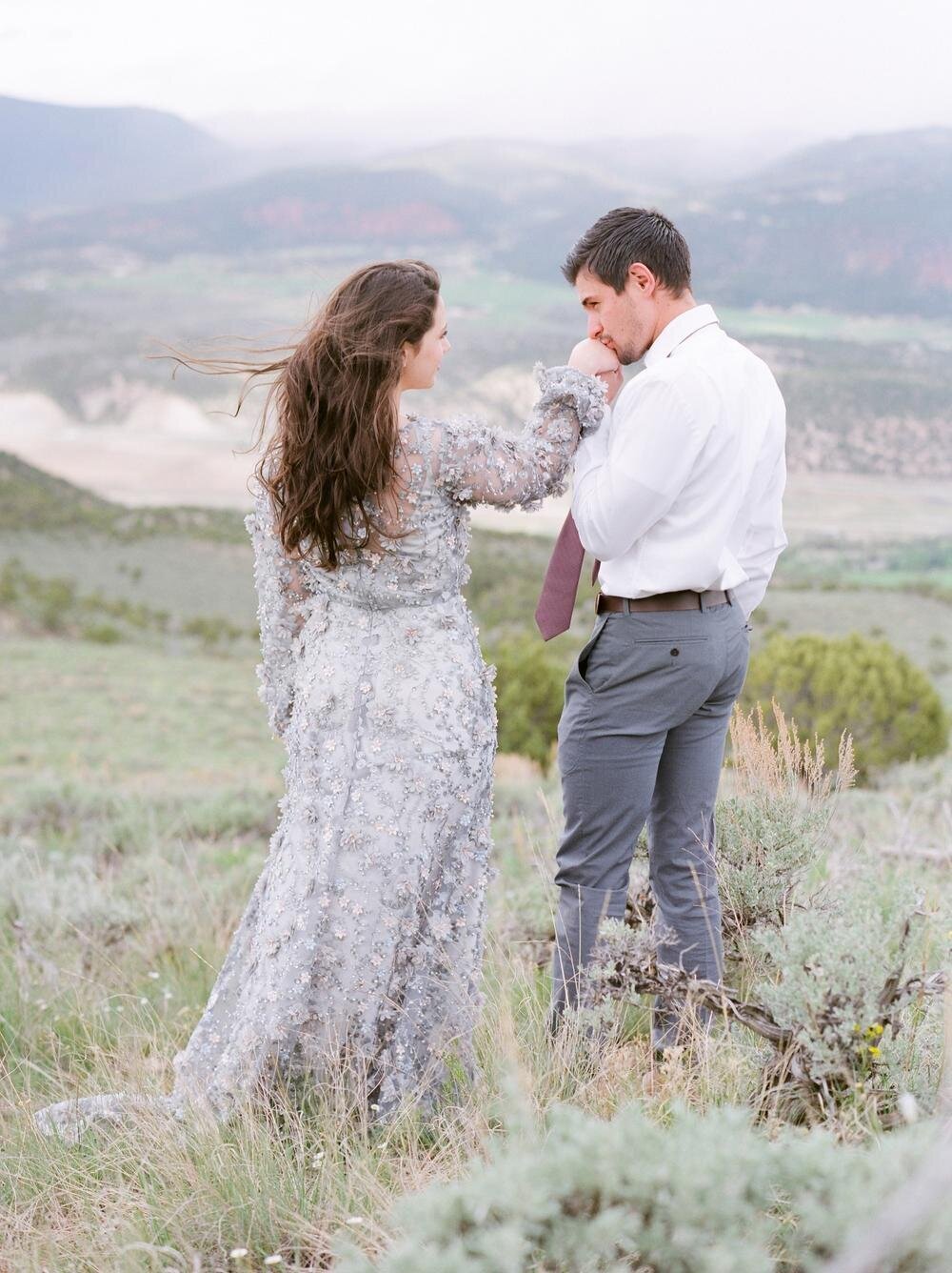 Man-kissing-woman’s-hand-white-looking-out-into-vail-Colorado-mountains-.jpg