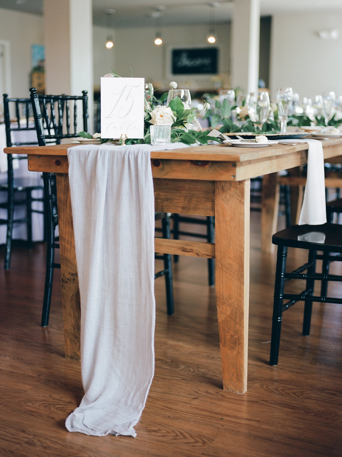 wooden table with black chairs and white table runner