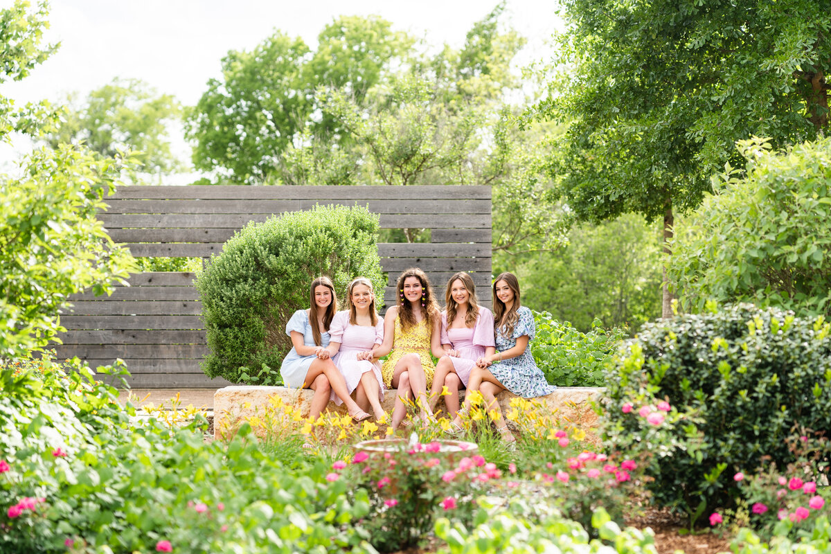Texas A&M senior girls wearing pastel colors and sitting together in the middle of a garden of Leaching Teaching Gardens