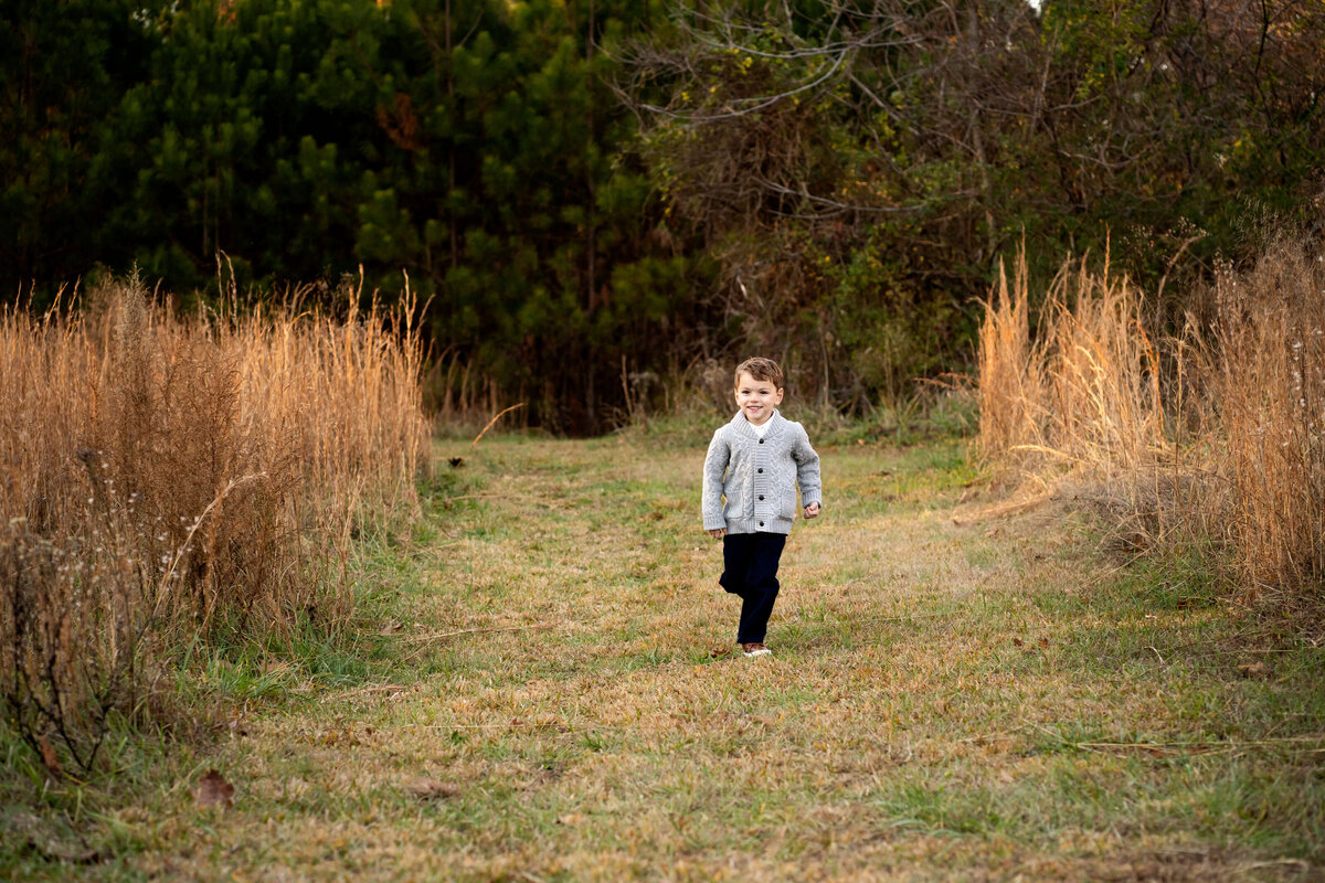 Young boy walking through field by Atlanta family photographer