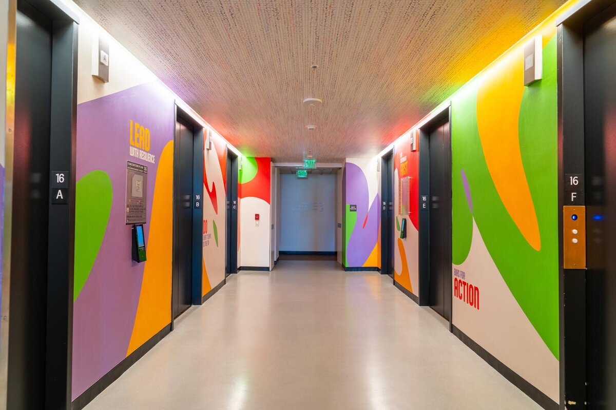 Colorful elevator lobby with large abstract murals on the walls and elevator doors labeled with floor numbers.