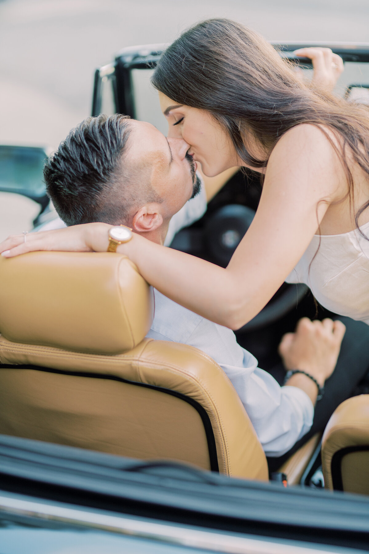 A passionate kiss shared between the couple in a vintage convertible, evoking timeless romance and cinematic storytelling
