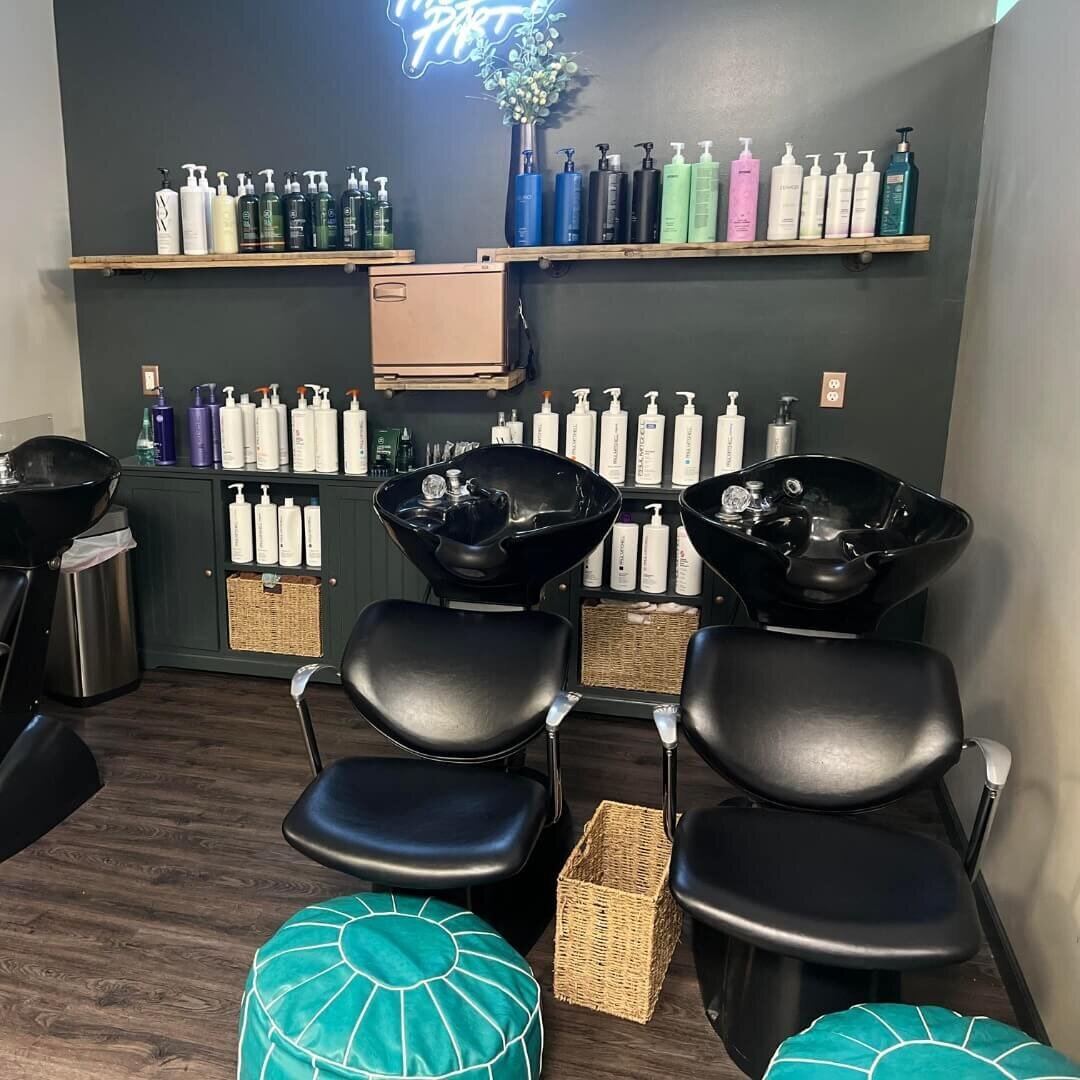 A modern and inviting shampoo station featuring black chairs and sinks, with a variety of hair care products neatly arranged on shelves, showcasing the professional and well-equipped facilities at 212 Salon, Spa, & Barbershop.