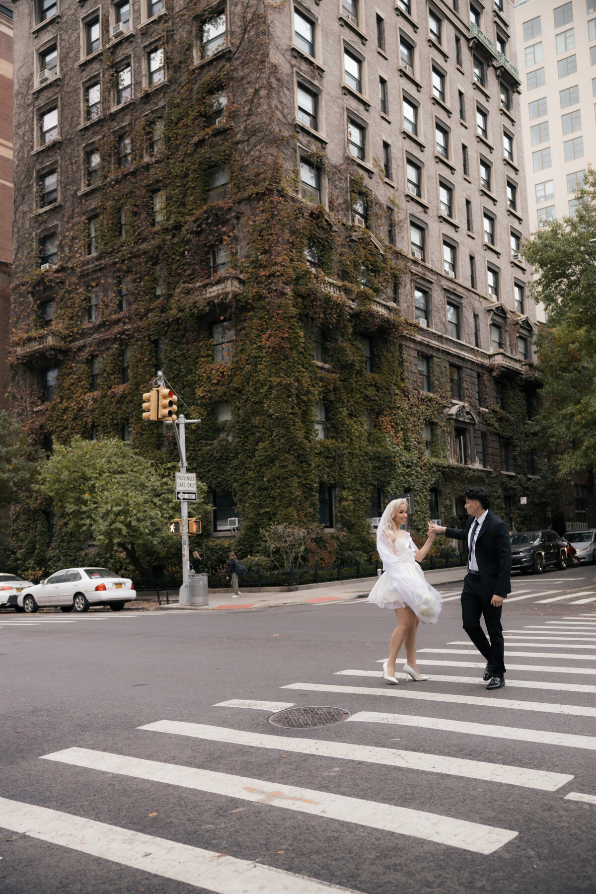 Couple standing close together on a sidewalk as city traffic moves behind them.