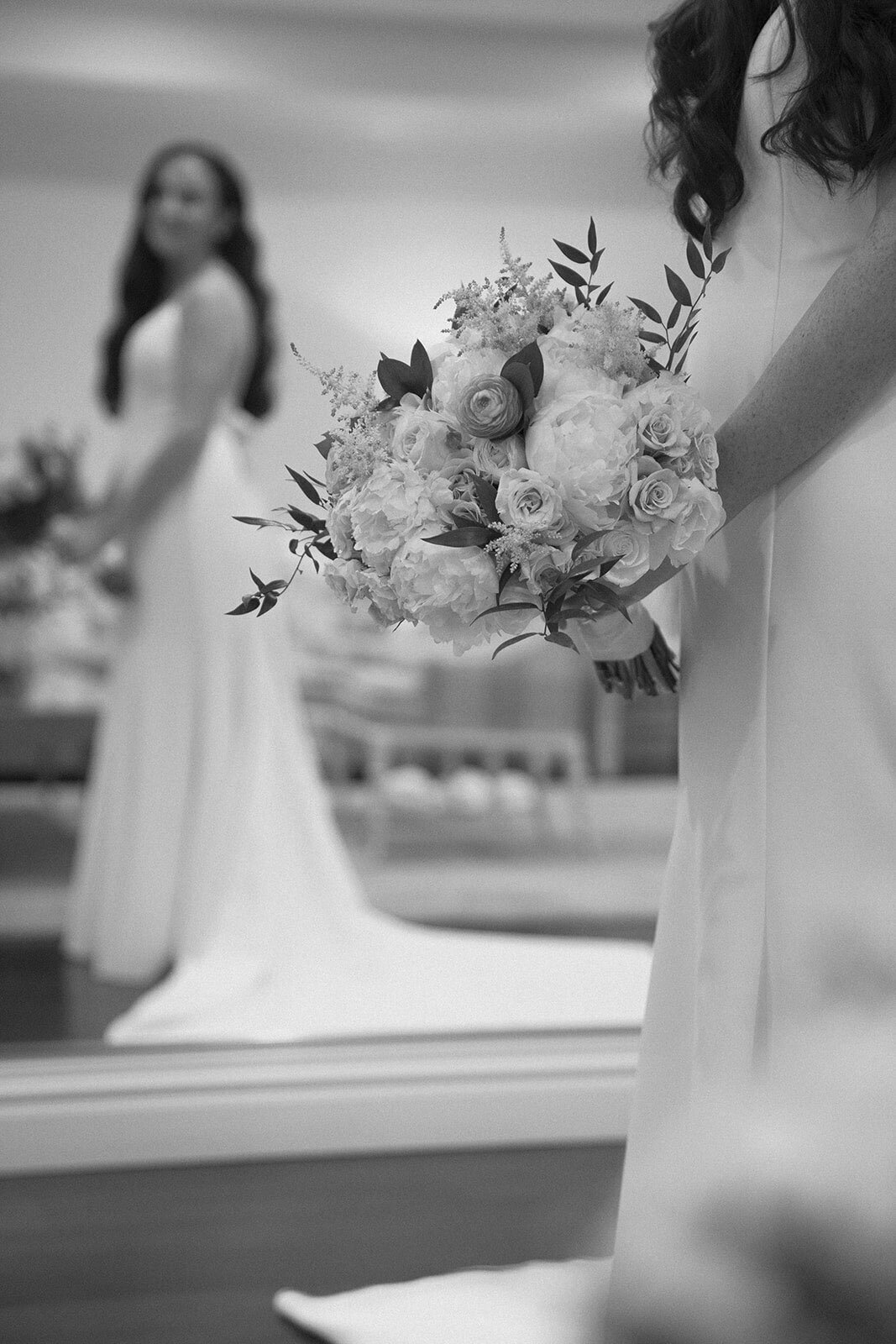 Bride standing with floral bouquet and bridesmaid in the background